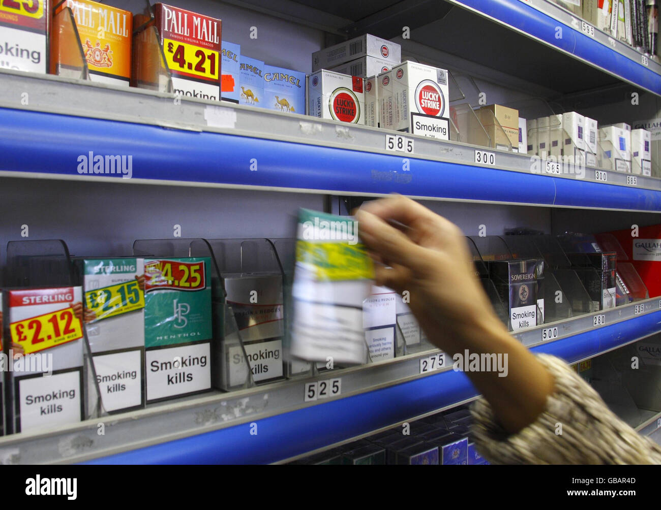 A shop assistant in Portsmouth reaches for a packet of cigarettes. Health Secretary Alan Johnson today unveiled plans to force cigarette sales 'under the counter' in a bid to cut smoking by children. Stock Photo