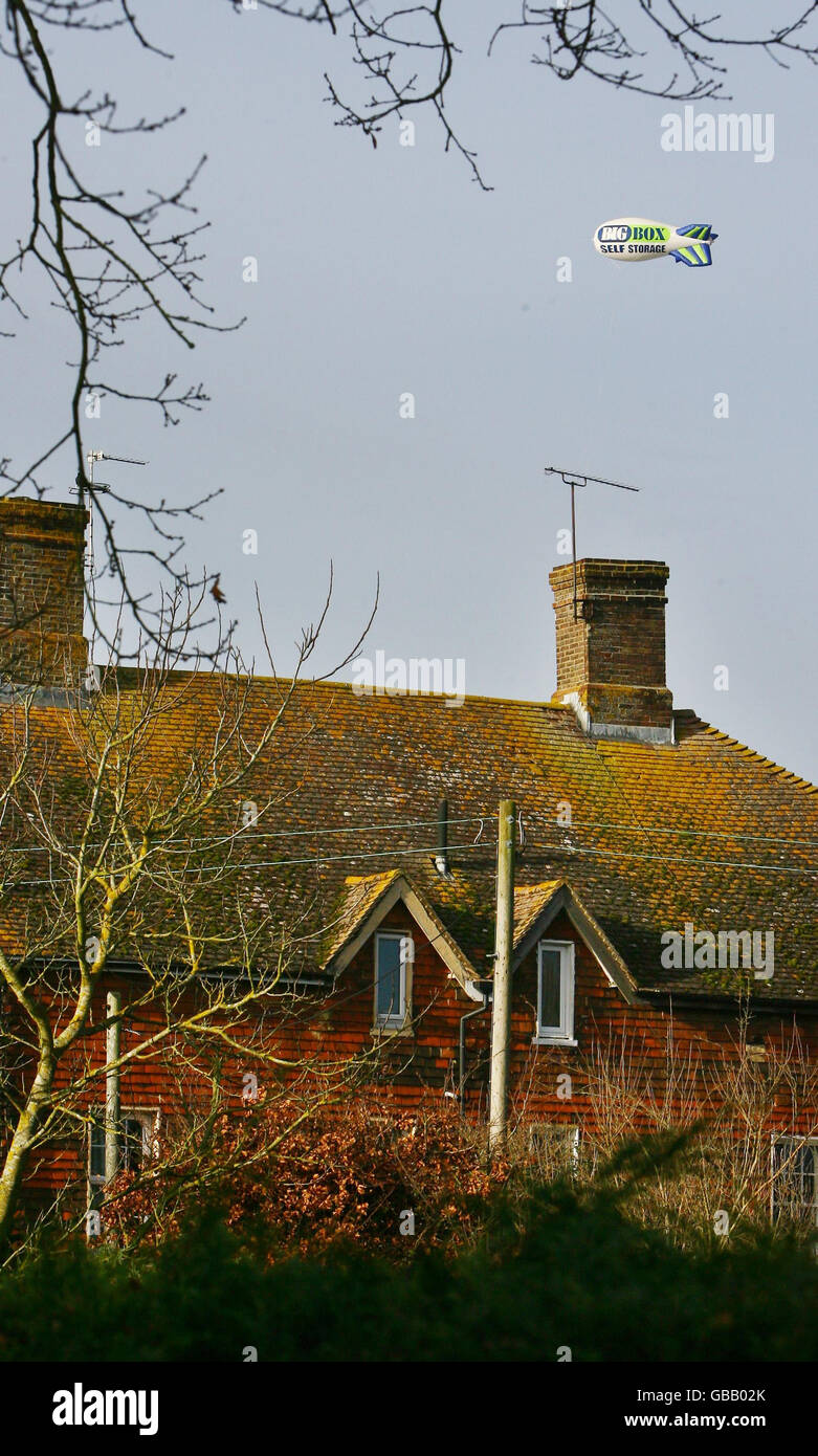 Blimp under fire. A house near Ditchling, in East Sussex is overshadowed by the Big Box Storage Centre blimp. Stock Photo