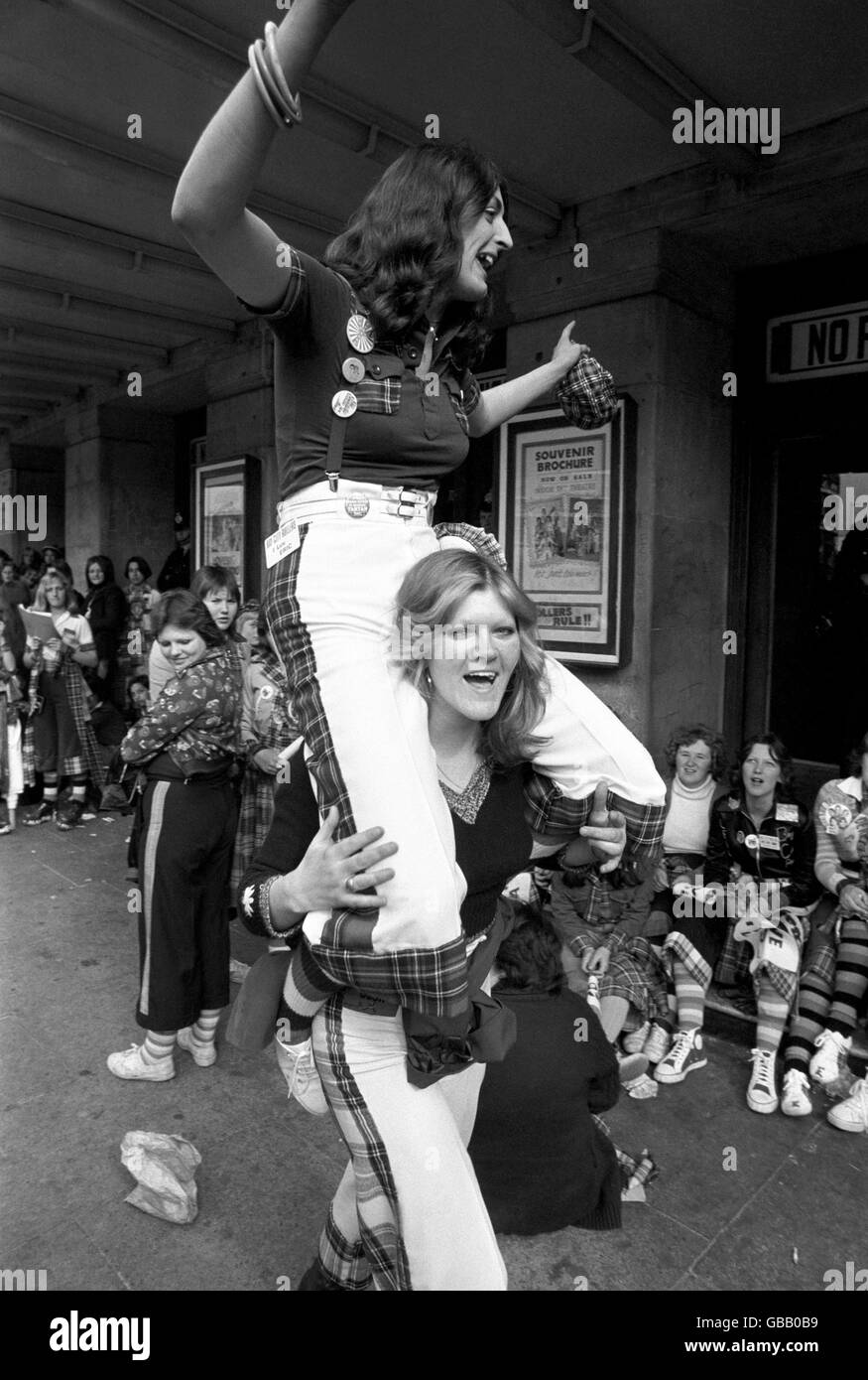 High spirits from two fans of the Bay City Rollers, as they wait with other fans for the doors to open at the Odeon, Hammersmith, for the first of two concerts by the group. Stock Photo
