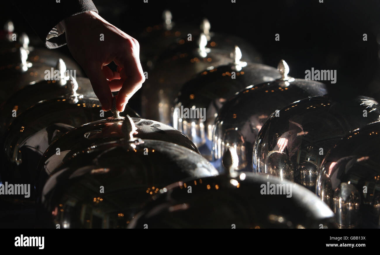 A visitor examines a set of silver plated cloches, as part of the closing down auction at the Cafe Royal, Piccadilly, London. Stock Photo