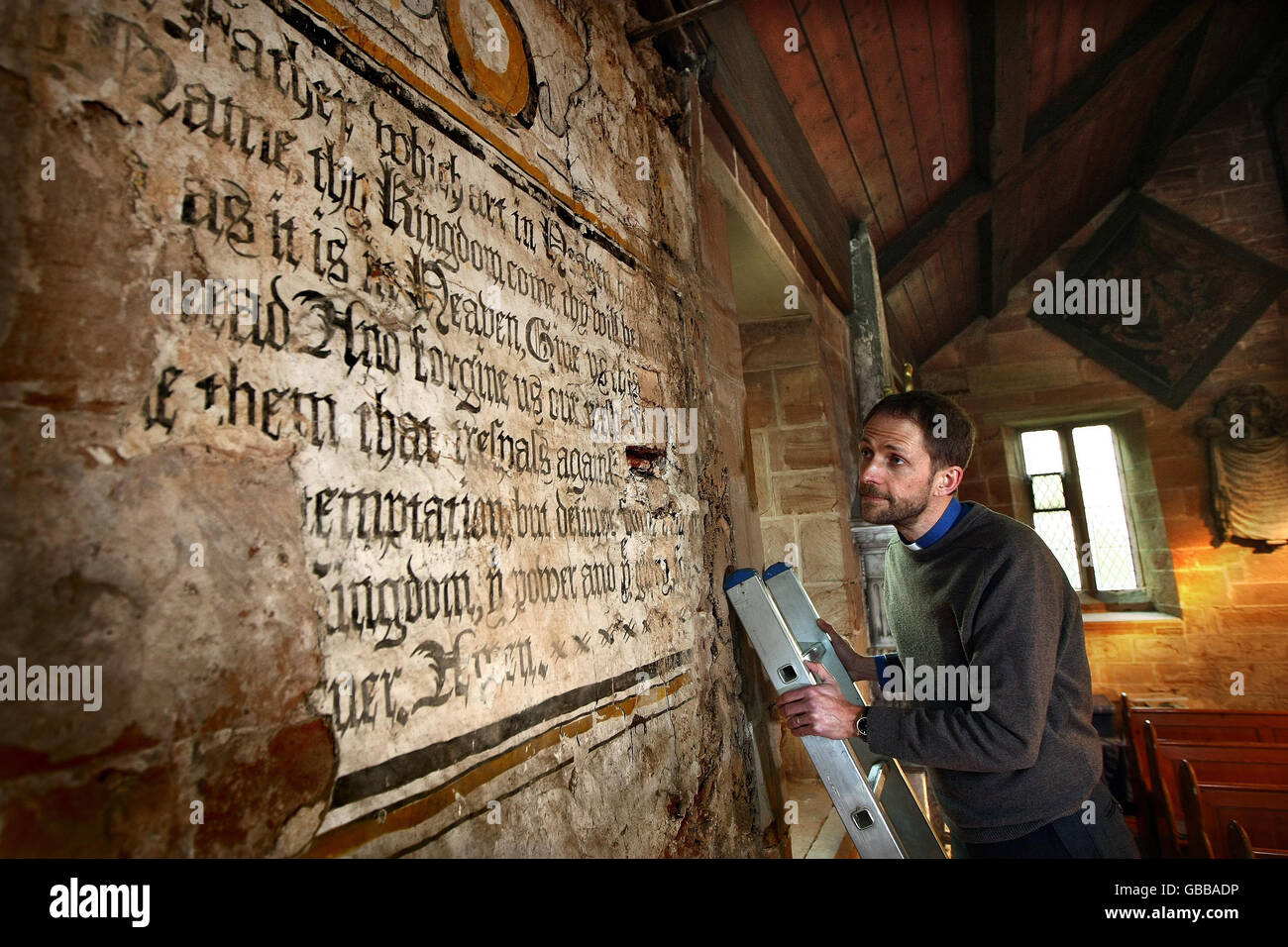 Reverend Dr Matthew Rhodes, vicar of St Chad's Church in Wishaw, Warwickshire, with a centuries-old mural of the Lord's Prayer, which has been hidden since 1673. Stock Photo