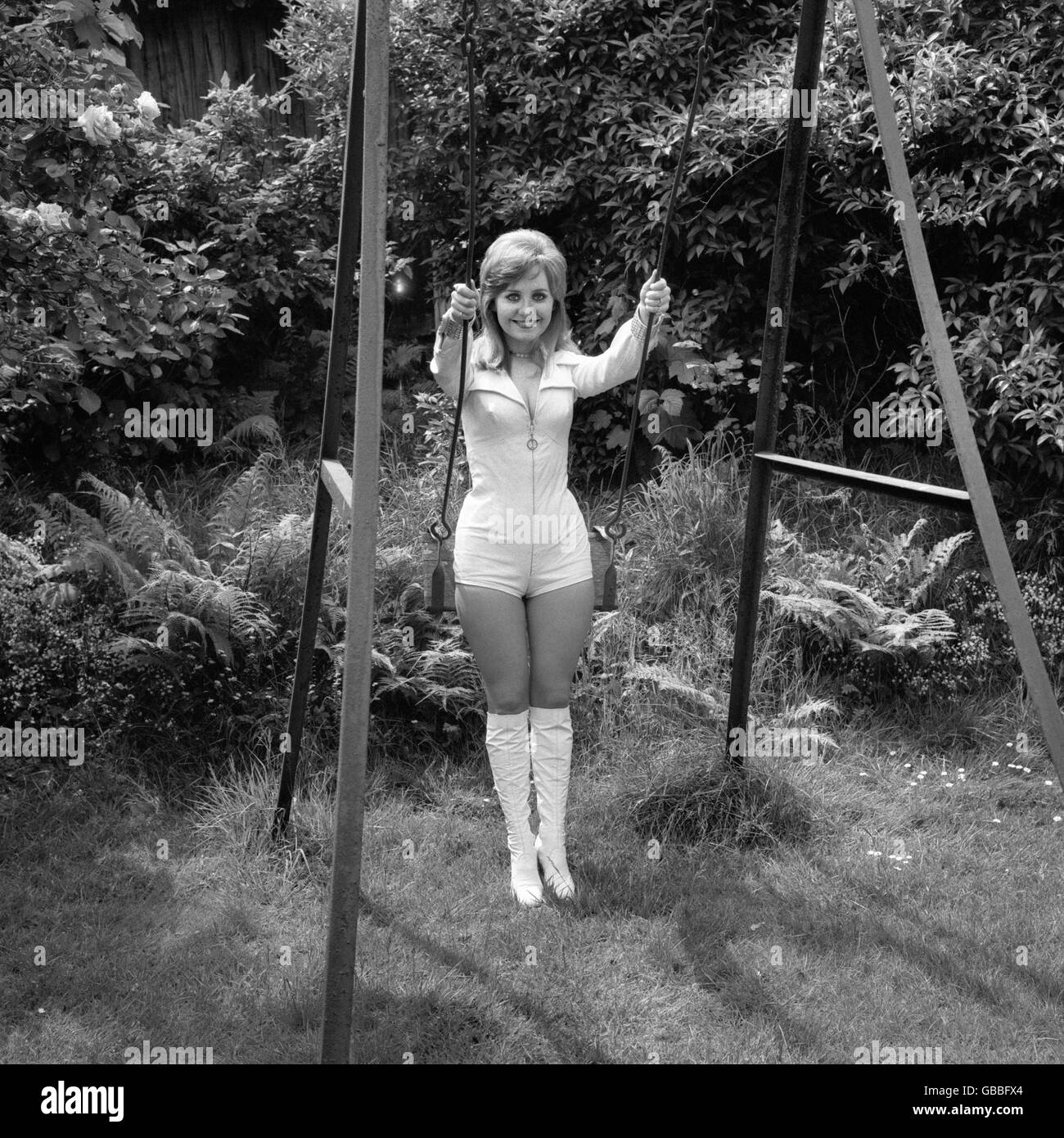 Singer Lulu wears a white leather hot pants outfit, as she relaxes on a swing at her Highgate home. Stock Photo