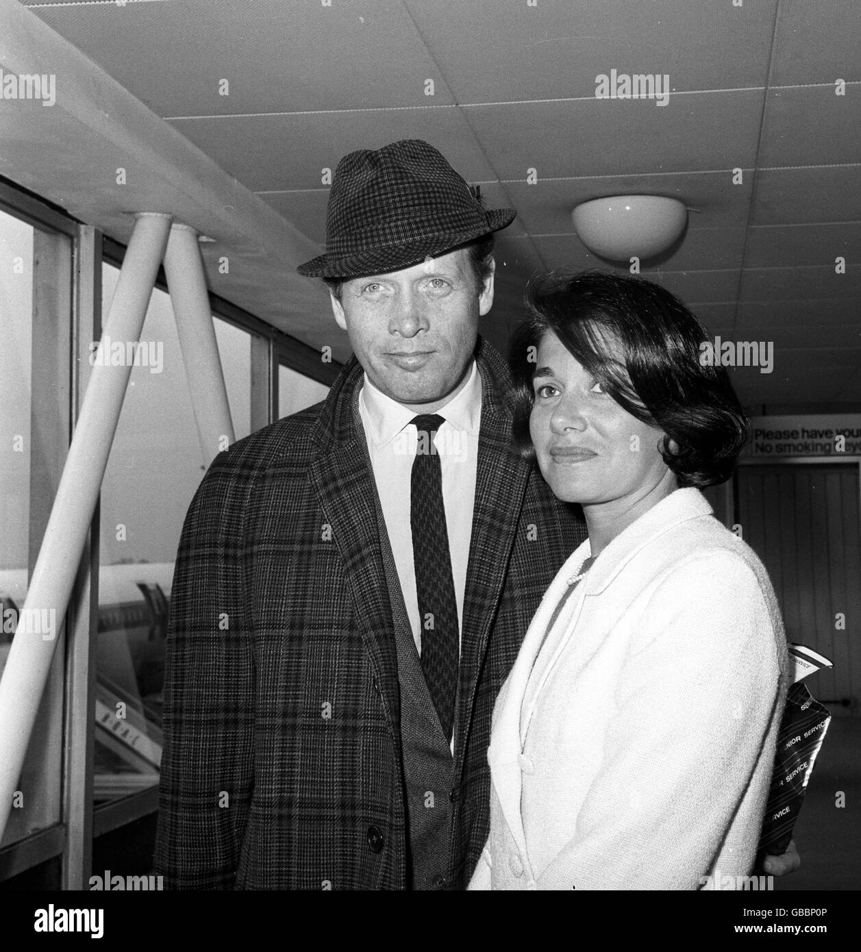 Actor Patrick McGoohan, better known to television viewers as John Drake of the 'Danger Man' series, pictured with wife on returning from a visit to America, at Heathrow Airport. Stock Photo