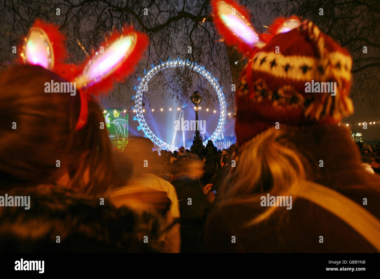 (left to right) Hannah and Jess Lyons, from Southampton in Hampshire, join thousands of other revellers as they enjoy themselves next to the River Thames opposite the London Eye and the Shell building, shortly before the capital was due to welcome in the New Year. Stock Photo