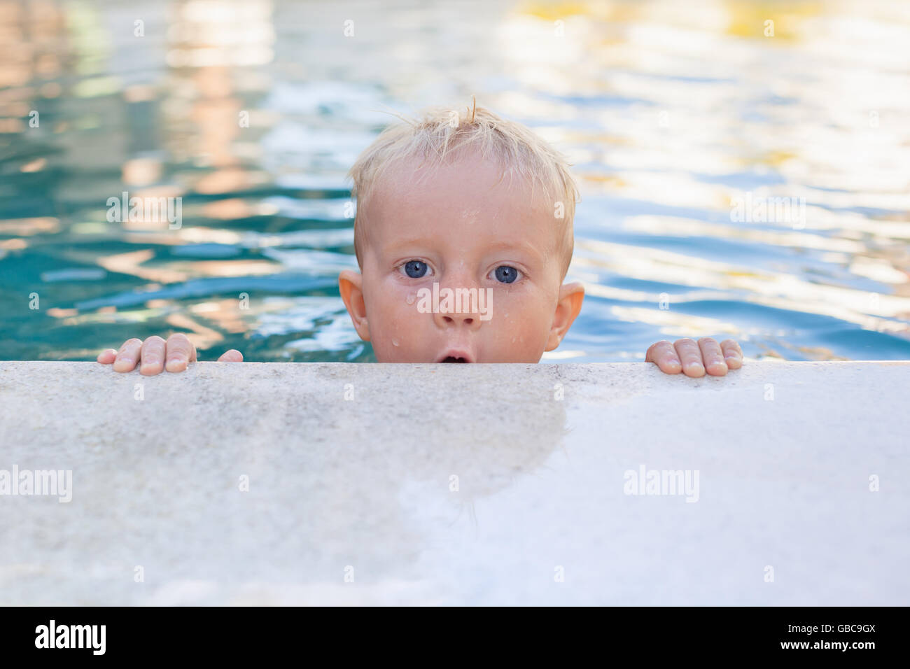 Child learn to swim - funny face of little baby boy in pool. Active healthy lifestyle, water sport, children physical activity. Stock Photo