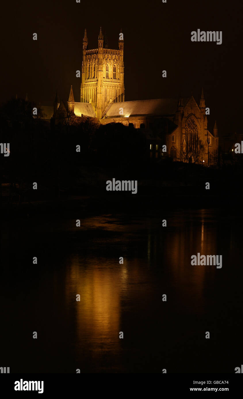 Worcester Cathedral stands with snow on it's roofs lit by floodlights besides the River Severn. Stock Photo
