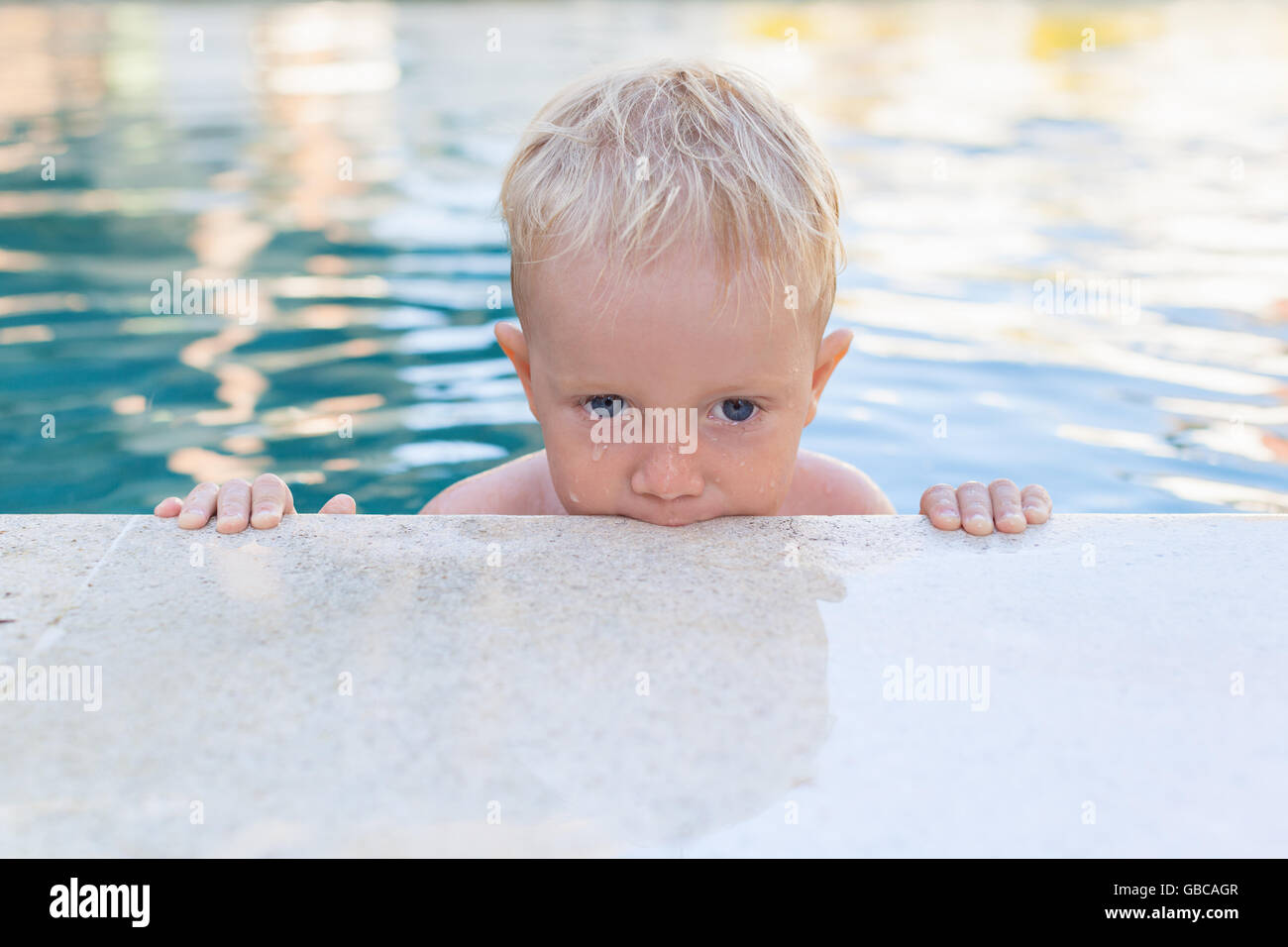 Child learn to swim - funny face of little baby boy in pool. Active healthy lifestyle, water sport, children physical activity. Stock Photo