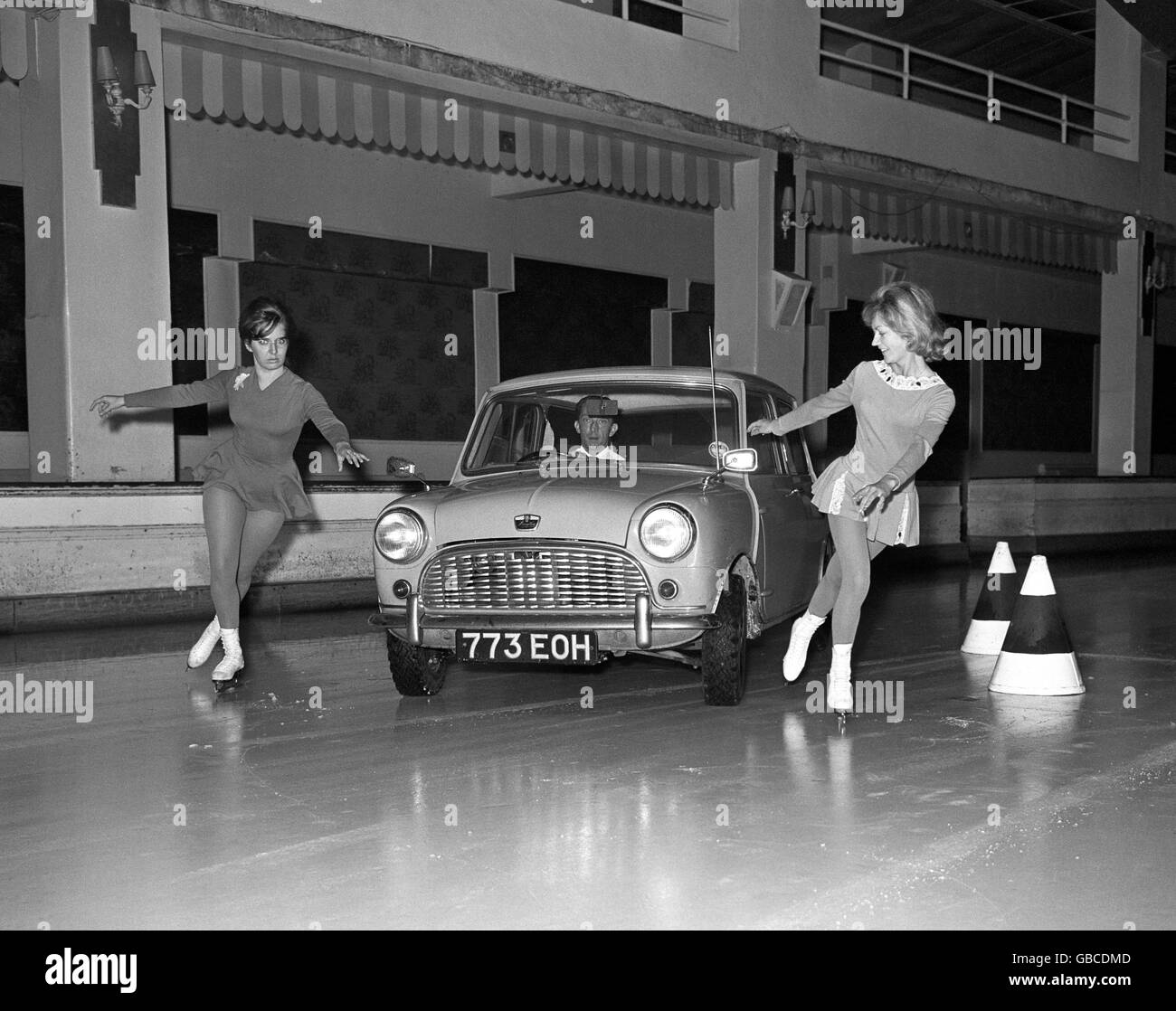 A BMC mini car fitted with new Dunlop ice tyres has no difficulty in following, even on the tightest corners, skaters Doreen Jewell and Ann Hinkin, left, during a demonstration at the Queen's Ice Skating Club rink in London. Stock Photo