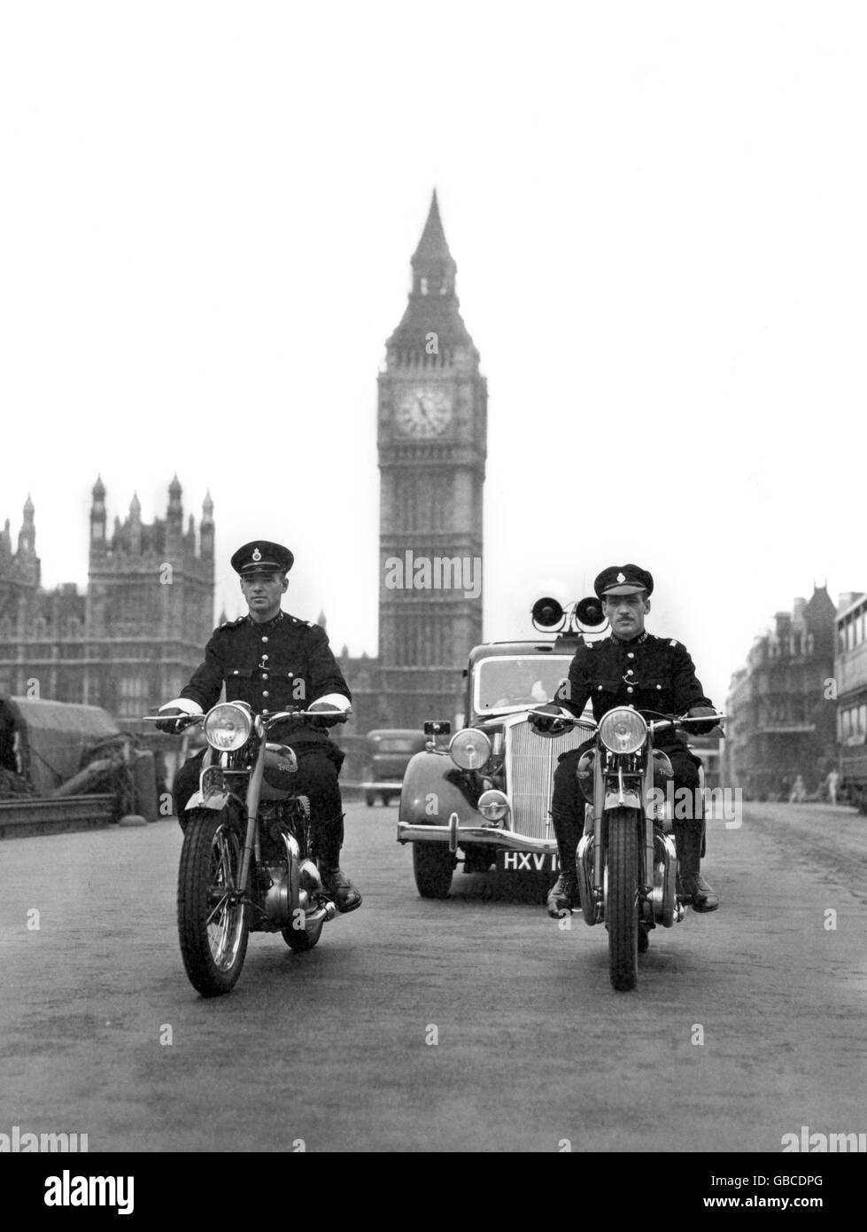 A new police radio-telephone directed police car of the new Traffic and Accident Group, Scotland Yard, crossing Westminster Bridge with attendant motor-cyclists. Stock Photo