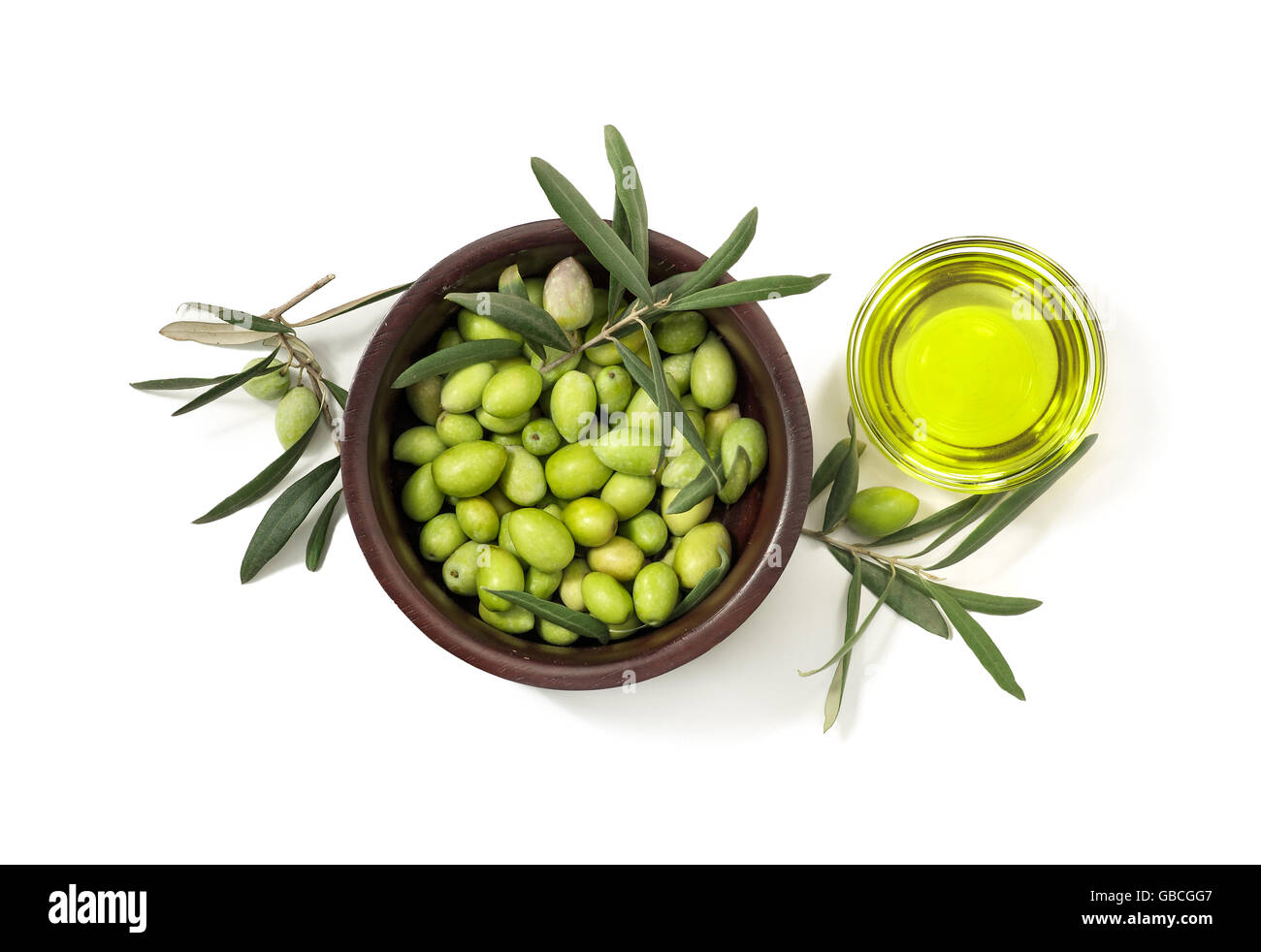 Green olives in wooden bowl and olive oil in glass bowl, isolated on white background. Top view Stock Photo