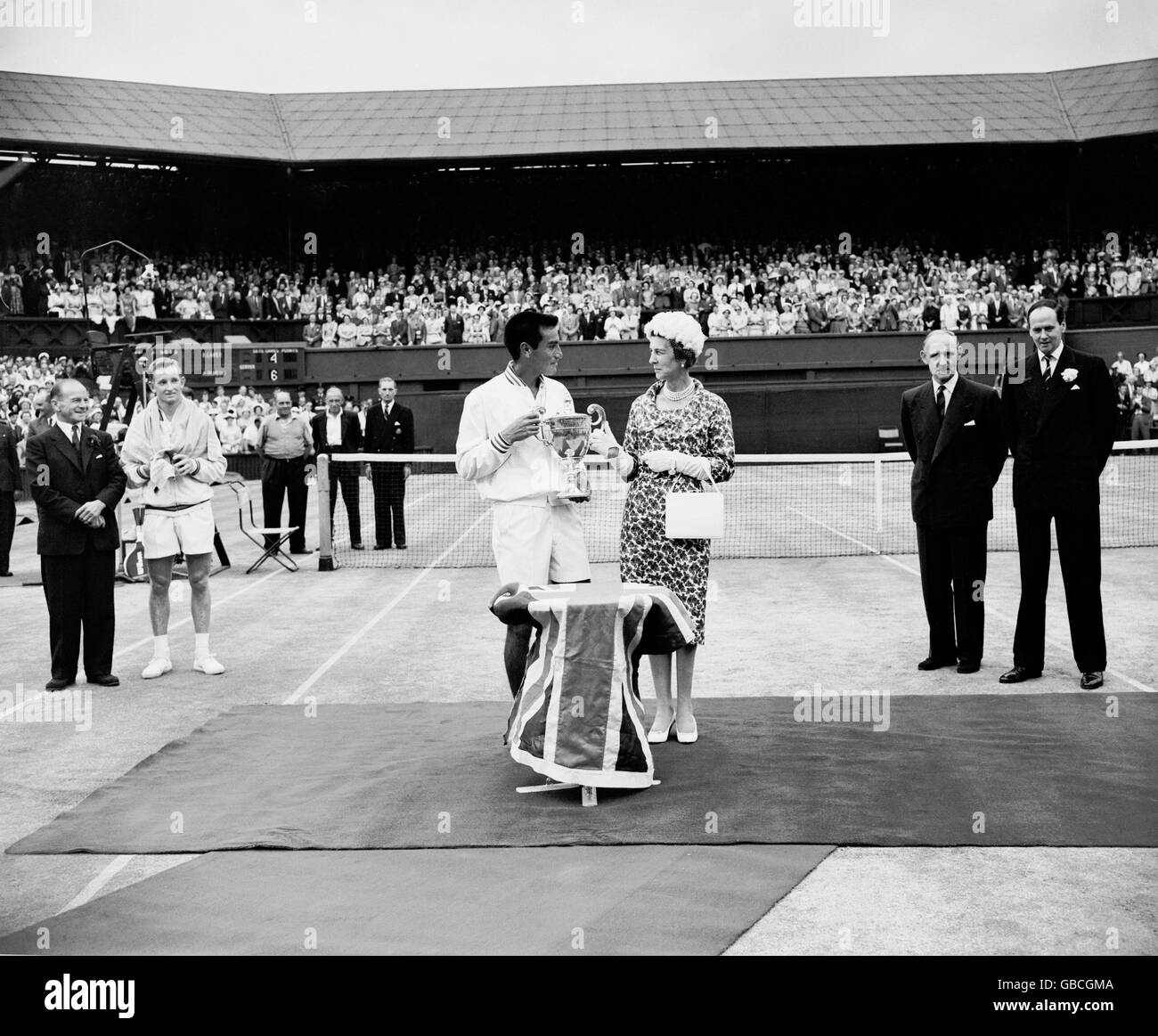 Tennis - Wimbledon Championships - Men's Singles - Final - Alex Olmedo v Rod Laver. HRH The Duchess of Kent presents the trophy to Alex Olmedo after his straight sets win, watched by runner-up Rod Laver (second l) Stock Photo