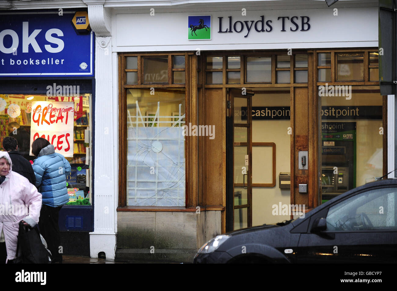 A taped broken window waits to be repaired at the Lloyds TSB Bank branch in Ilkley, it is not know how or why the window was broken. Stock Photo