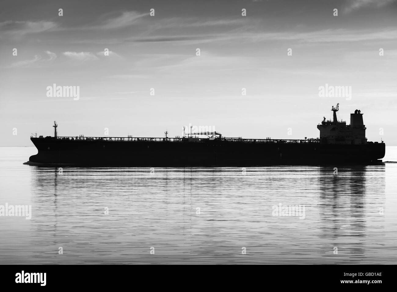 Big industrial tanker ship goes on still sea water, black and white silhouette photo Stock Photo