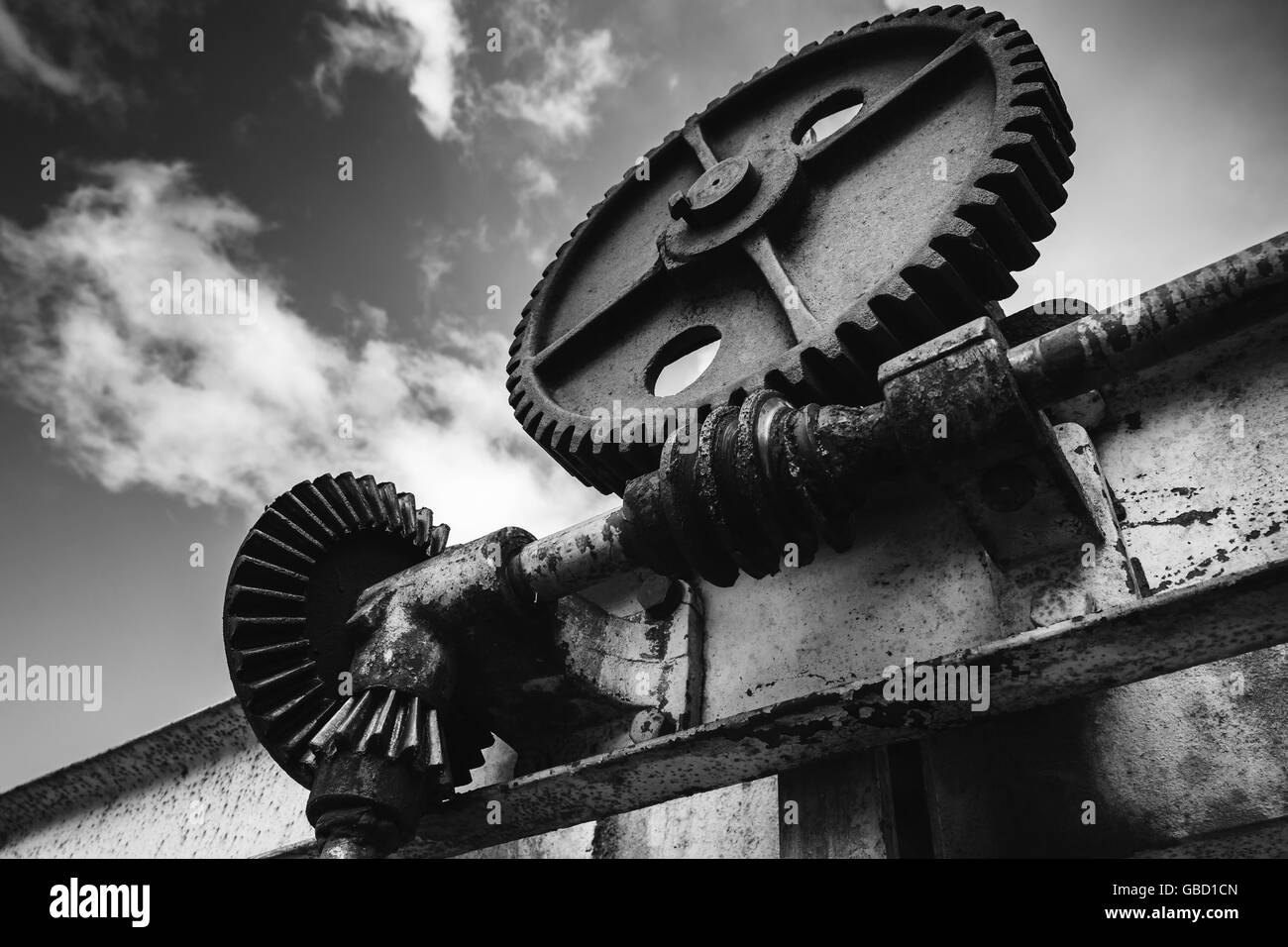 Old rusted gears under dramatic sky background, close-up black and white photo with selective focus Stock Photo