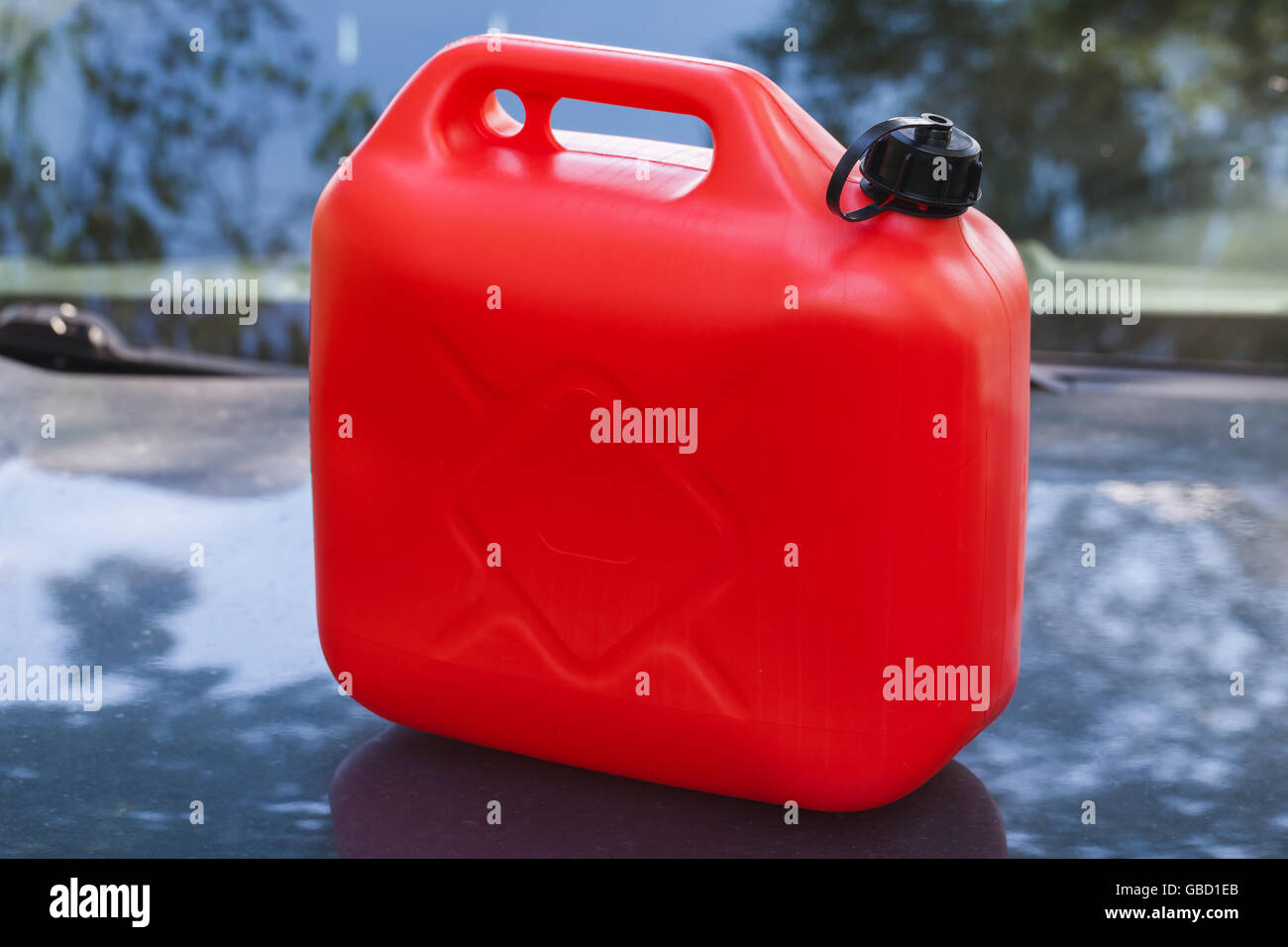 Red plastic jerry can stands on a car hood Stock Photo