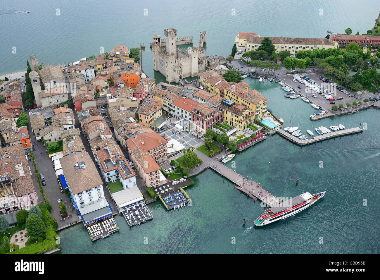 AERIAL VIEW. Medieval castle in a unique 'aquatic' setting on the shore of Lake Garda. Sirmione Peninsula, Province of Brescia, Lombardy, Italy. Stock Photo