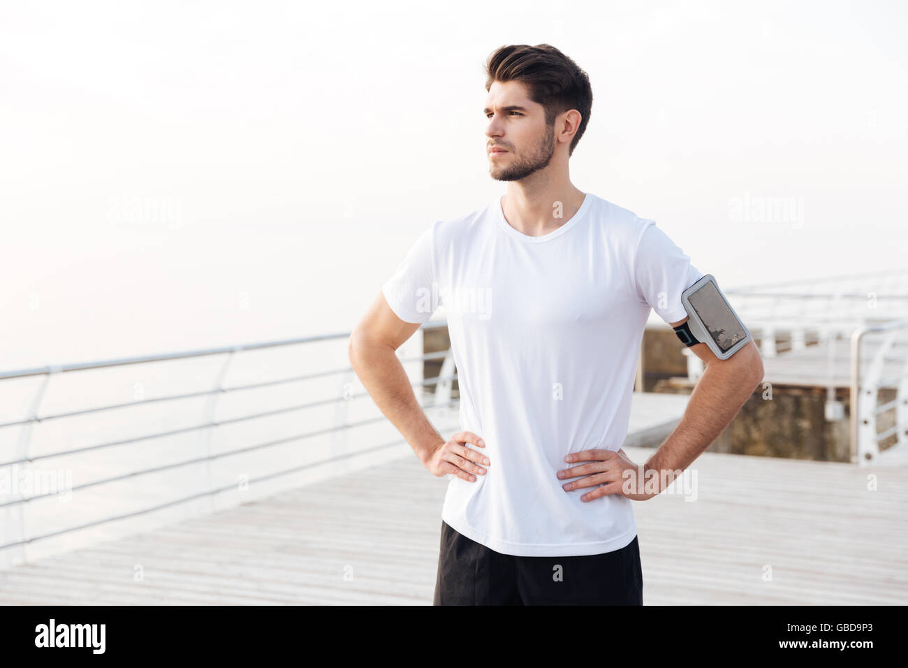 Portrait of confident young sportsman with mobile phone in armband Stock Photo