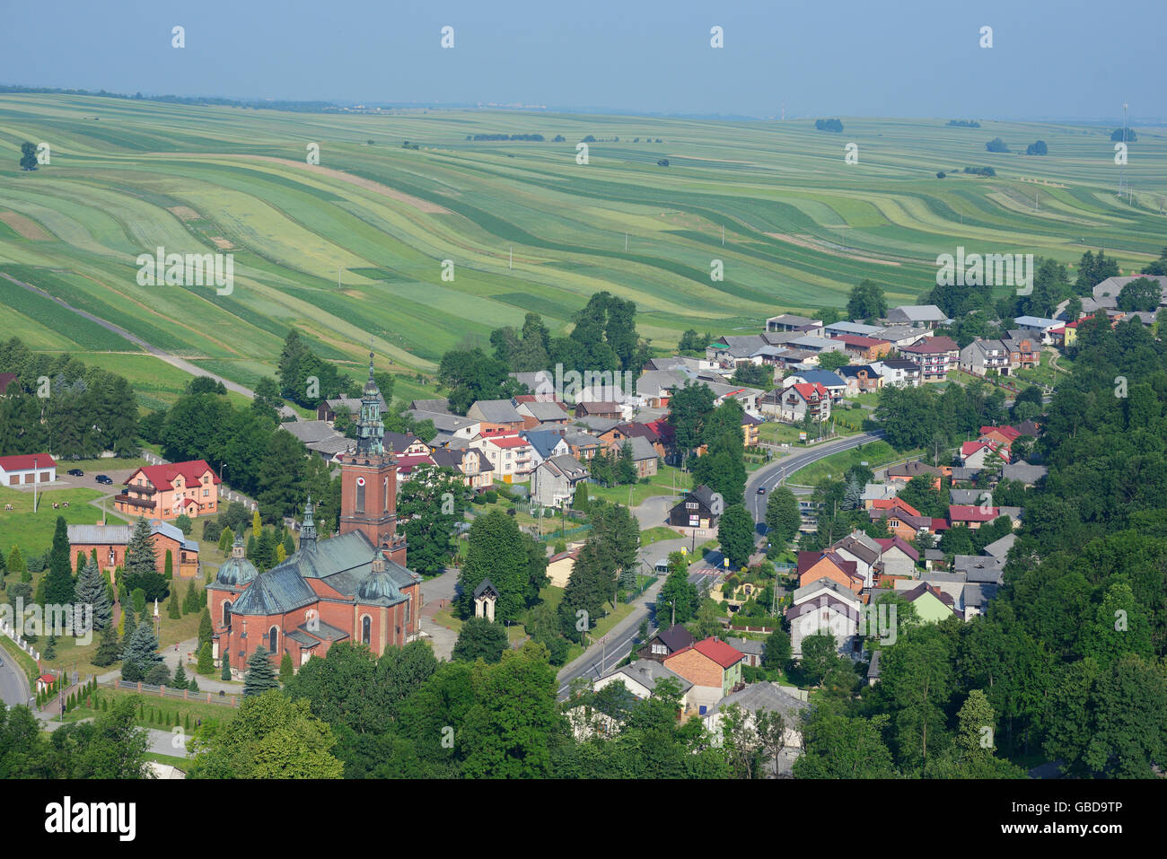 AERIAL VIEW. Village surrounded by a landscape of green narrow fields. Suloszowa, Lesser Poland Region, Poland. Stock Photo
