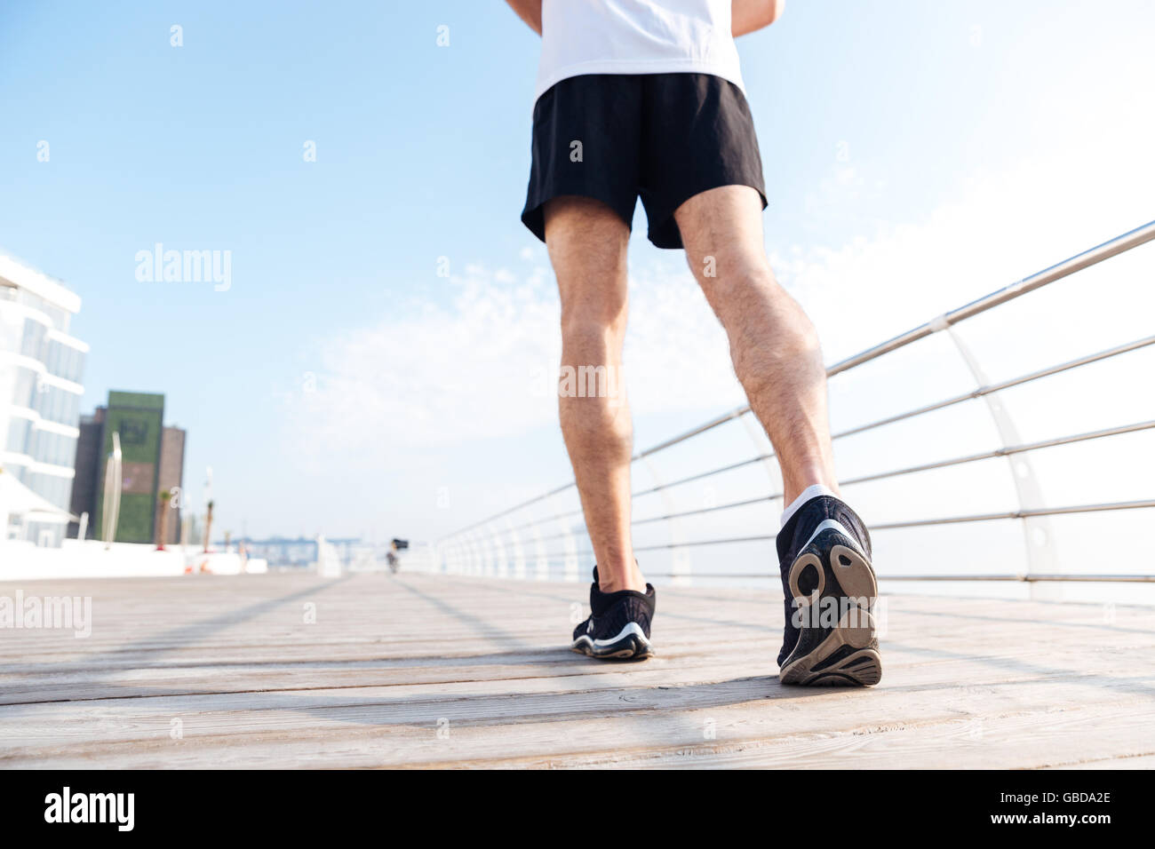 Back view of legs of young man in black shorts and sneakers running on pier  Stock Photo - Alamy