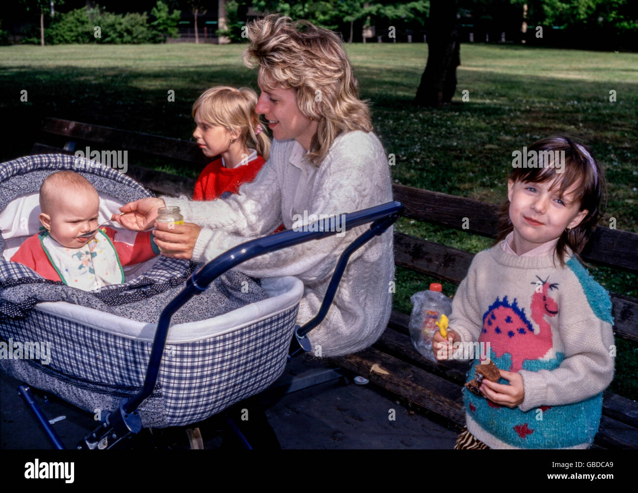 Mother with her three daughters on a walk in the park, Prague, Czech Republic family baby in stroller woman three children Stock Photo