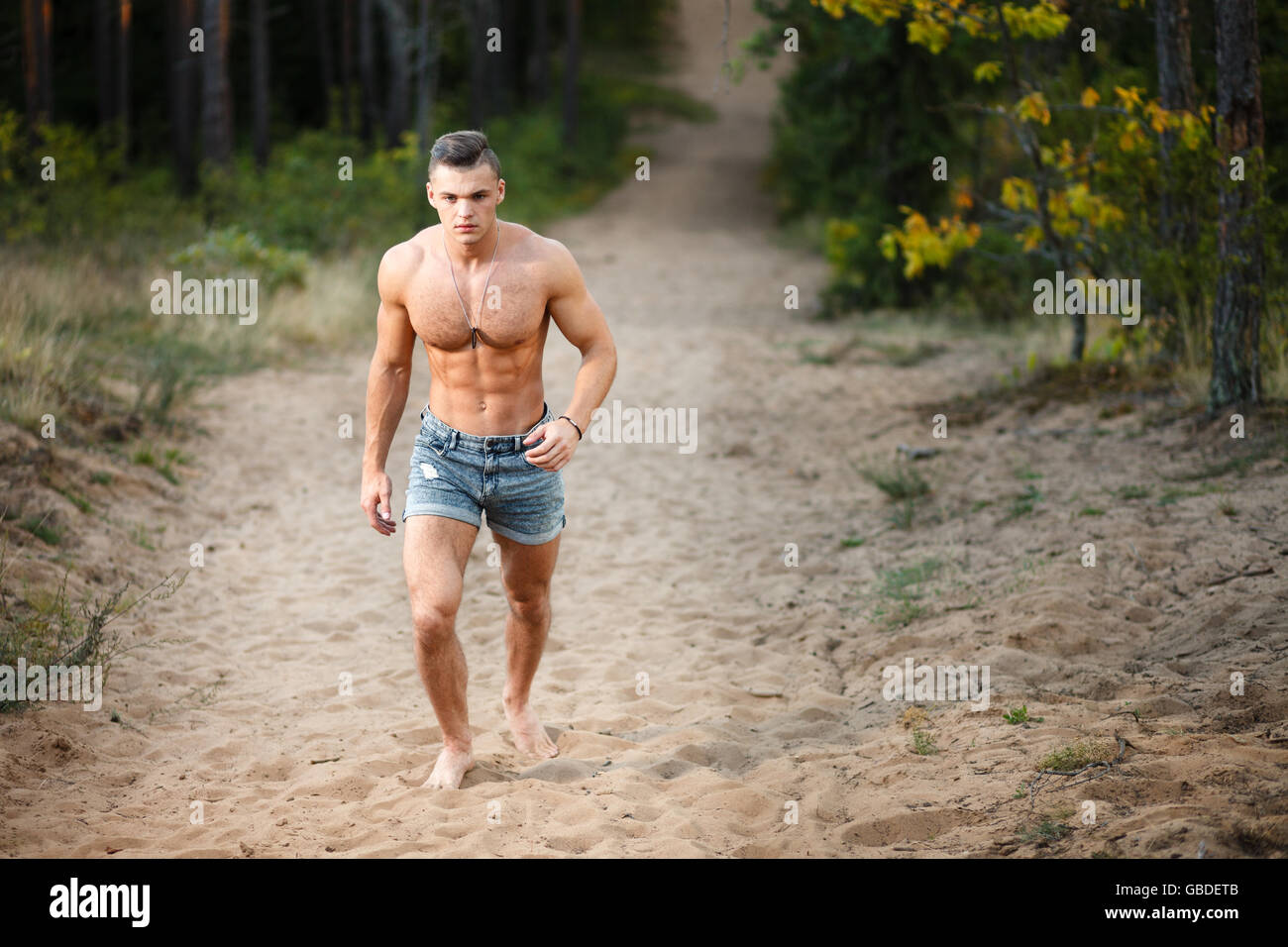 Muscular young man running at forest. Stock Photo