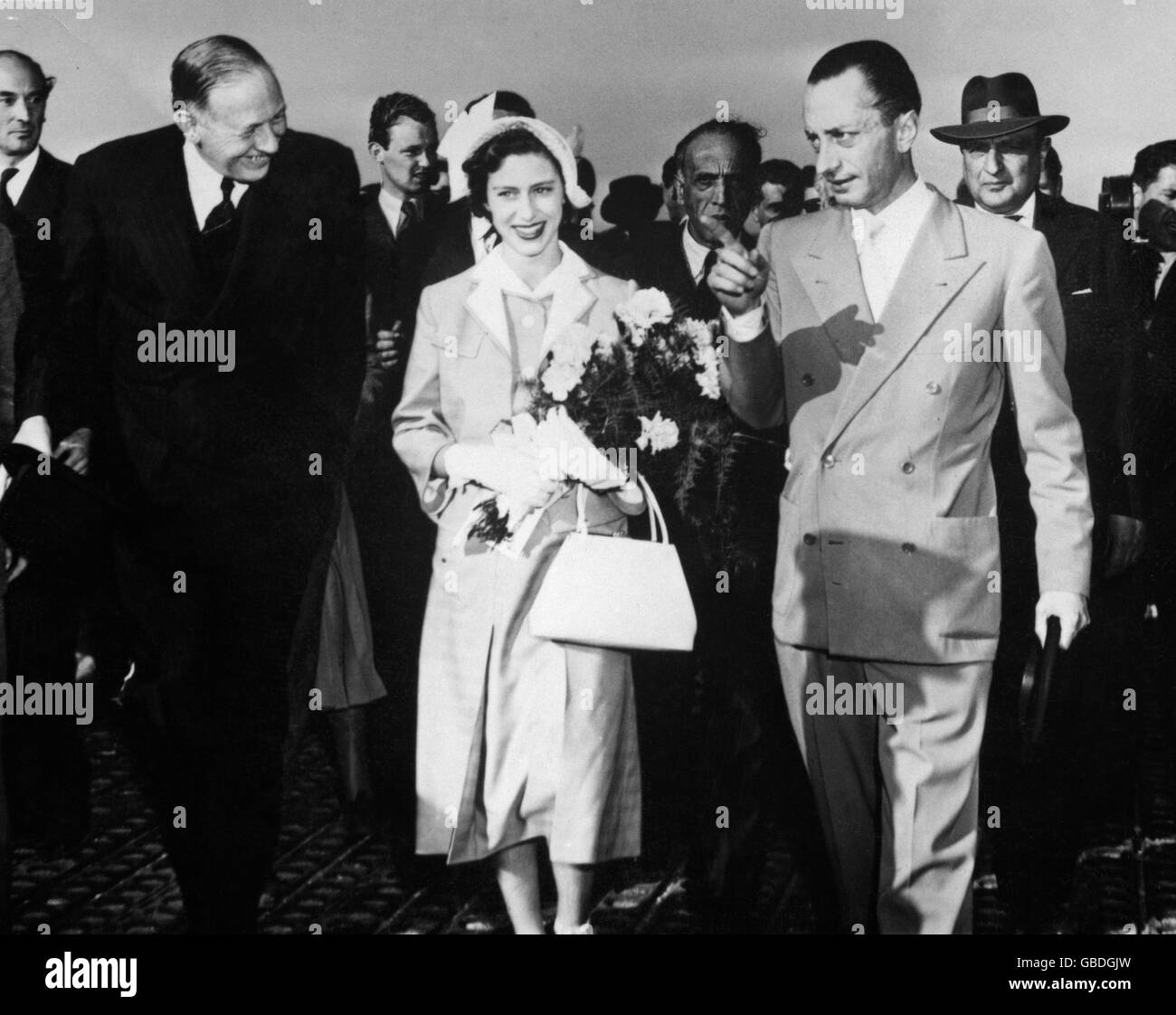 Princess Margaret smiles in the sunshine of Naples as, carrying a bouquet, she leaves the airfield there to begin her holiday in Italy. Stock Photo
