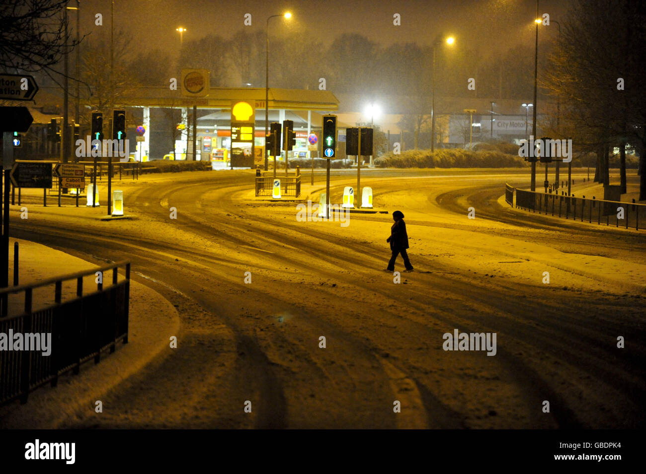 A woman crosses what is usually a very busy junction on the A4 main artery at Arnos Vale into Bristol from Bath in the early morning after heavy snowfall over the city and the south west of England. Stock Photo