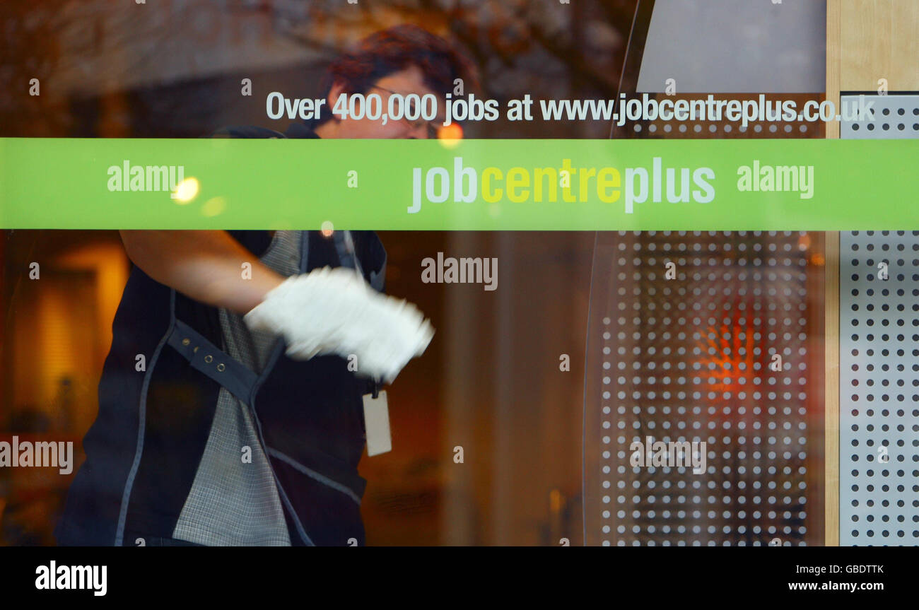 A cleaner wipes the windows of the Job Centre Plus shop in central