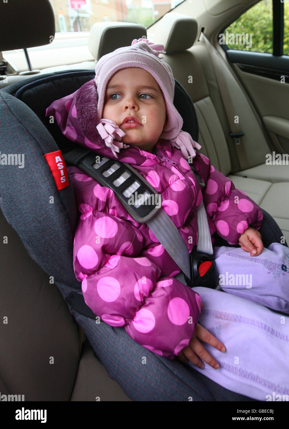 Child seat safety. A young girl prepares for a journey in a child's car seat near Ashford in Kent, as a survey reveals two in three car seats are not fitted properly. Stock Photo