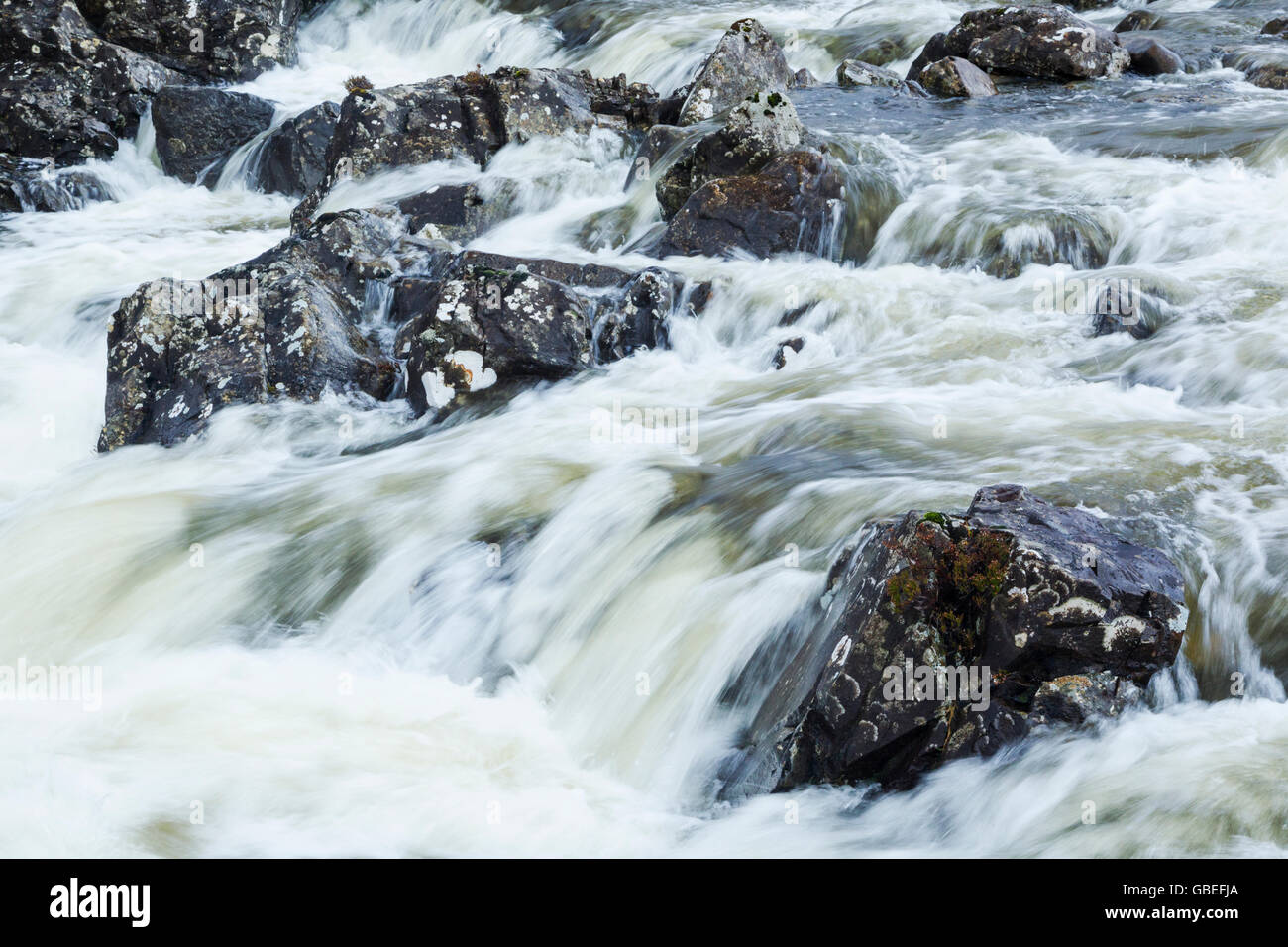 Energetic and aggressive river flowing between boulders Stock Photo