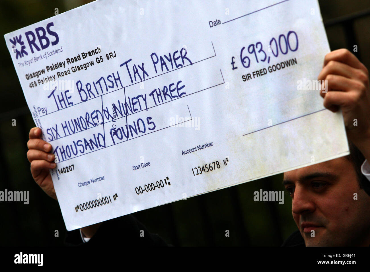 A national newspaper journalist holds a fake check outside the Edinburgh home of Sir Fred Goodwin today. Gordon Brown today voiced his 'anger' over the 693,000-a-year pension awarded to the former boss of Royal Bank of Scotland Sir Fred Goodwin, which the Prime Minister described as 'unjustifiable and unacceptable'. Stock Photo