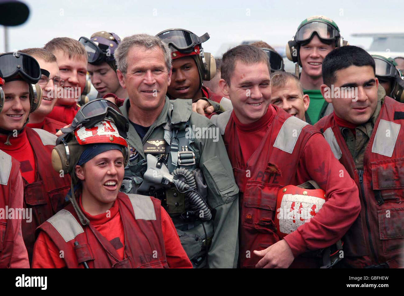 U.S. President George W. Bush poses for a photo with sailors on the flight deck after landing in a S-3B Viking aircraft on the aircraft carrier USS Abraham Lincoln during a visit May 1, 2003 in the Pacific Ocean. The Lincoln in returning from a 10-month deployment to the Arabian Gulf in support of Operation Iraqi Freedom. Stock Photo