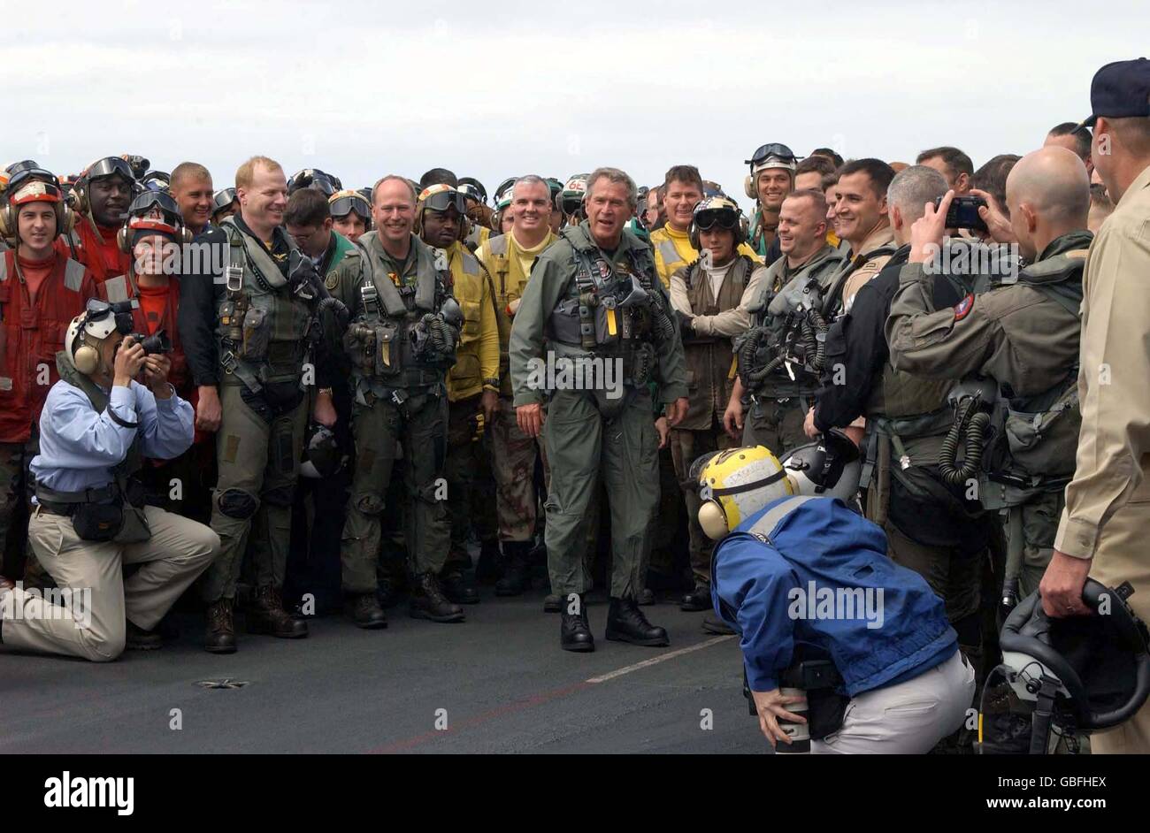 U.S. President George W. Bush poses for a photo with sailors on the flight deck after landing in a S-3B Viking aircraft on the aircraft carrier USS Abraham Lincoln during a visit May 1, 2003 in the Pacific Ocean. The Lincoln is returning from a 10-month deployment to the Arabian Gulf in support of Operation Iraqi Freedom. Stock Photo