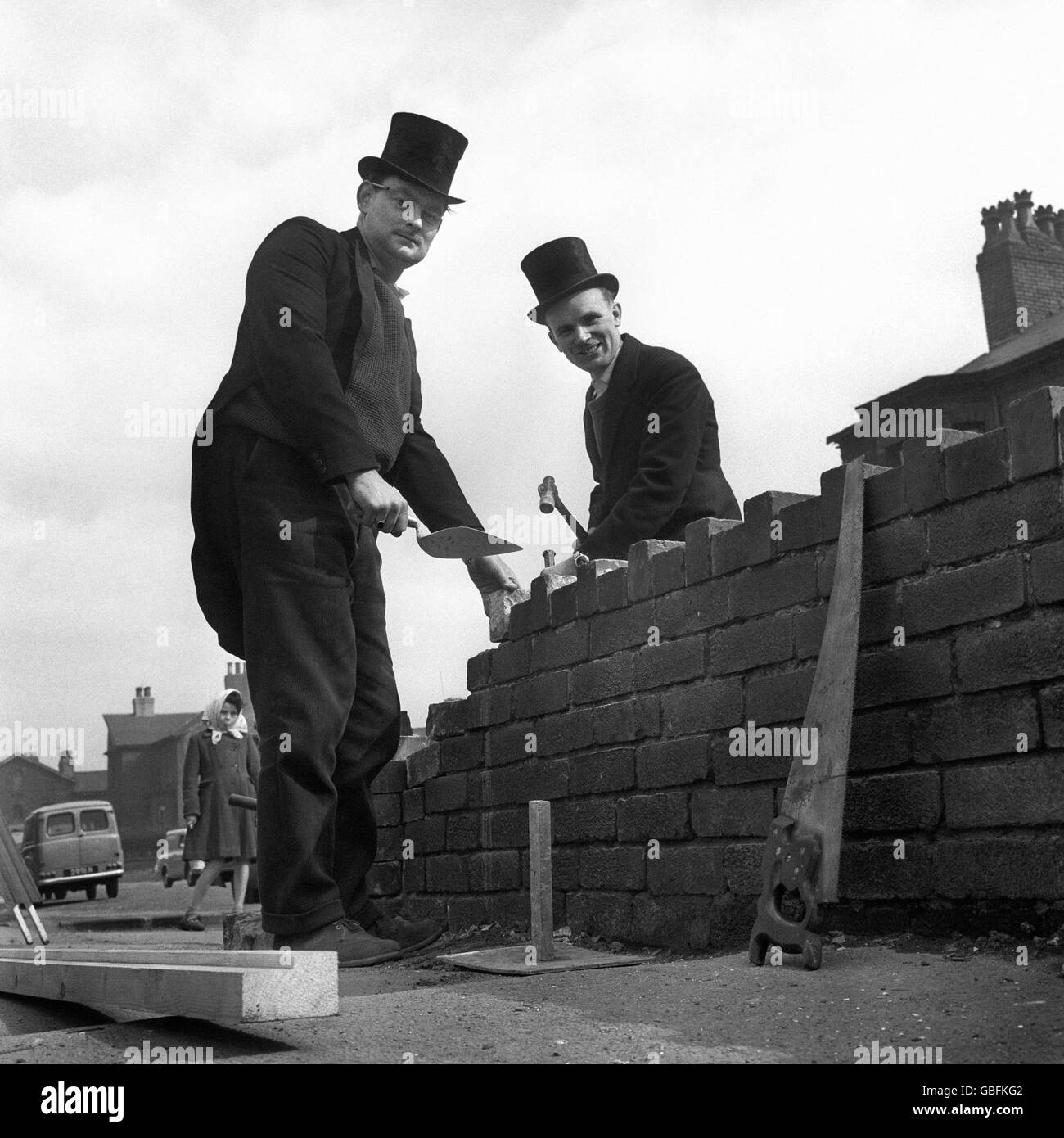 Wearing top hats and tails as they build a wall in Manchester are Malcolm West, 31, of Levenshulme, Manchester (left) and Colin Whittaker, 26, of Edgeley, Stockport, who run their own building business. Stock Photo