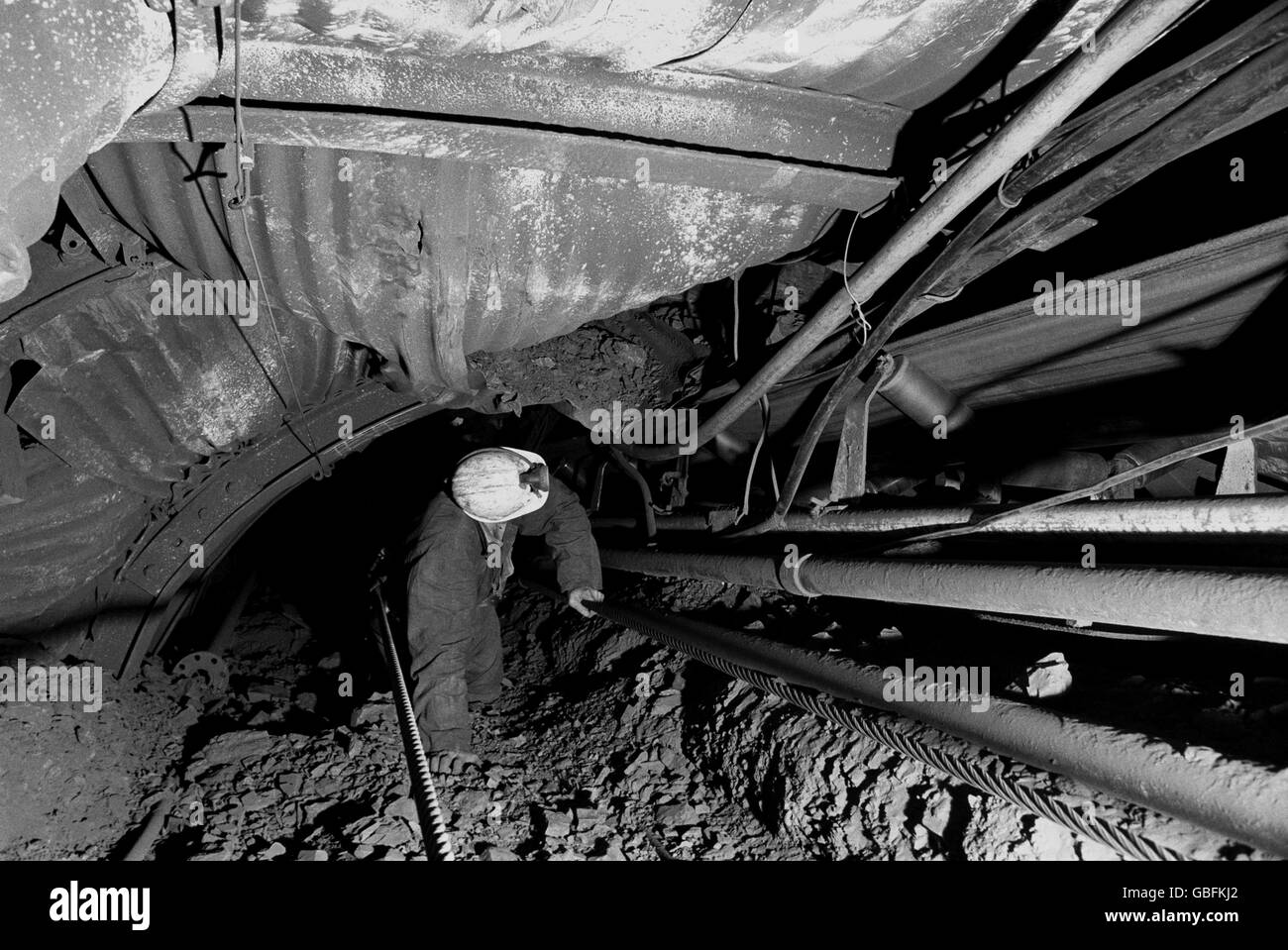 A pit official at Sutton Colliery near Mansfield, Nottinghamshire, checks on a trunk conveyor at the coal face. Stock Photo