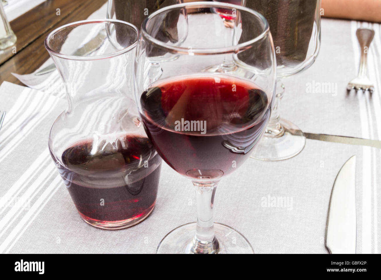 Outside table laid for eating with carafe and glass of red wine. Stock Photo