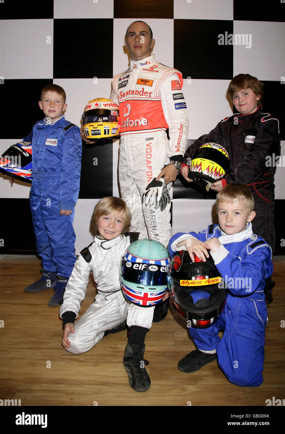 Four young members of the Buckmore Park Karting Club in Kent - the karting club where Hamilton was discovered - (left to right) Dave Wooder, 9, Billy Monger, 9, Myles Apps, 8 and Archie Tillett, 8, stand next to a waxwork of Formula One World Champion Lewis Hamilton as it is unveiled at Madame Tussauds in central London. Stock Photo