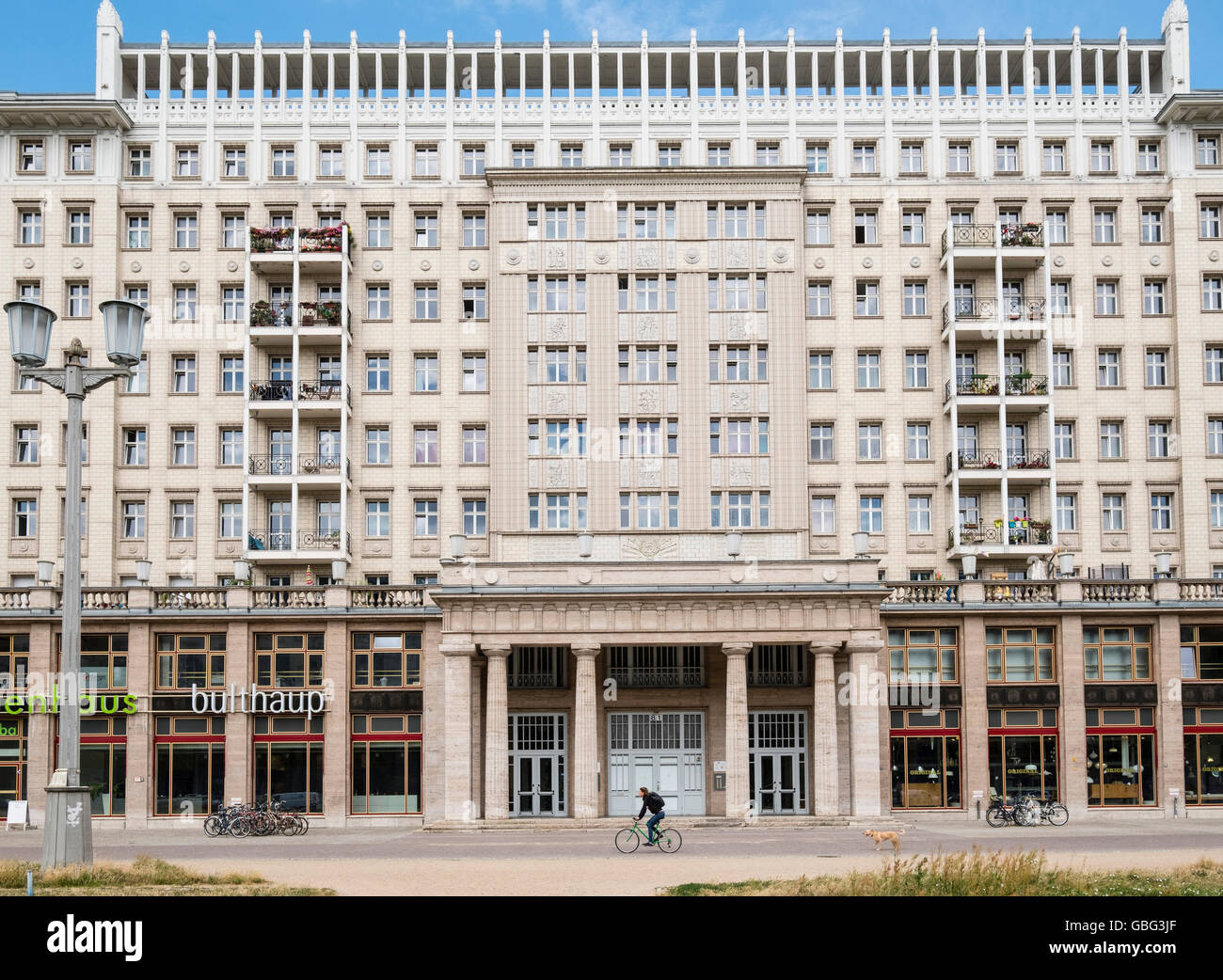 Cyclist rides past historic socialist former East German apartment buildings on Karl Marx Allee in Berlin Germany Stock Photo