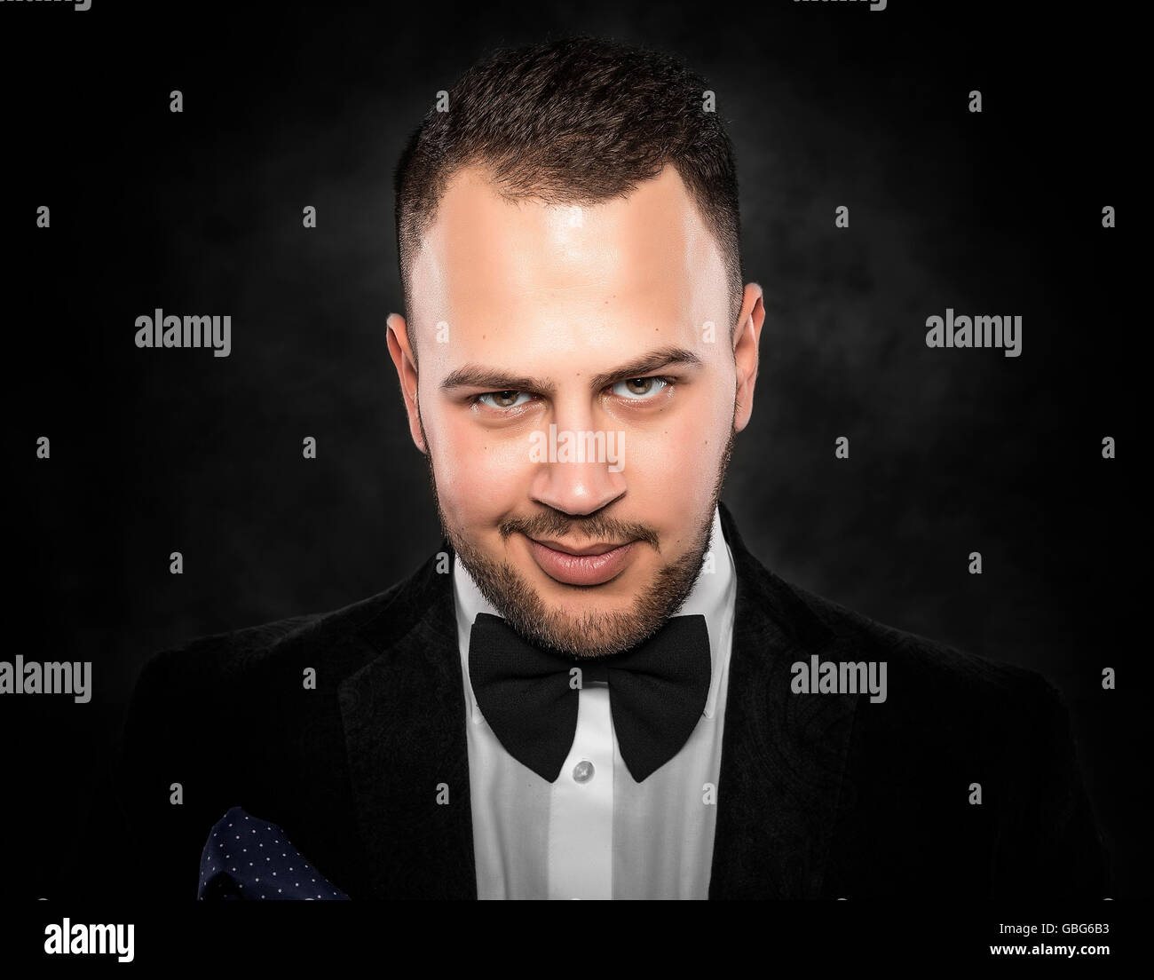 Young handsome man in black suit on dark background. Stock Photo