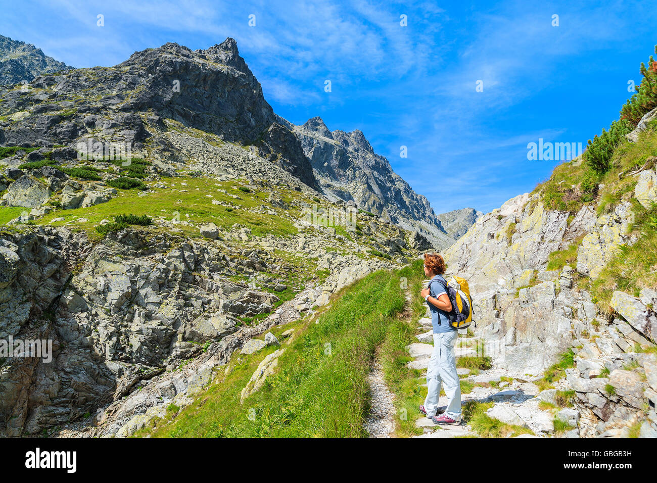 Young woman backpacker standing on hiking trail in summer landscape of High Tatra Mountains, Slovakia Stock Photo