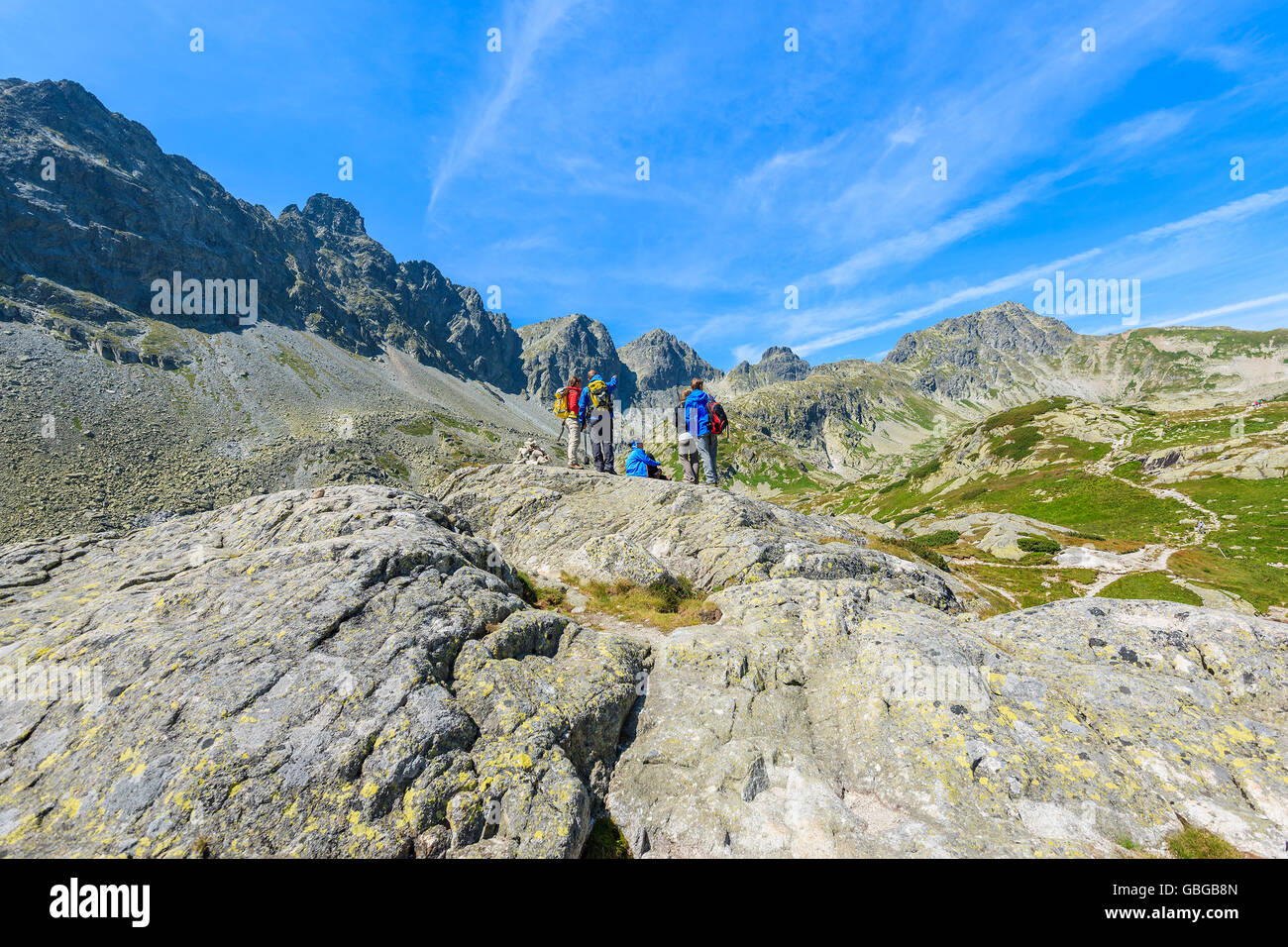 Group of tourists on top of rock looking at peaks of Starolesna valley in summer season, High Tatra Mountains, Slovakia Stock Photo
