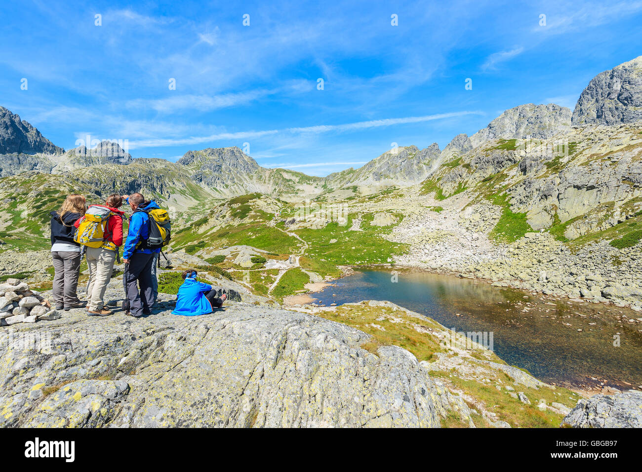 Group of tourists on top of rock looking at peaks of Starolesna valley in summer season, High Tatra Mountains, Slovakia Stock Photo