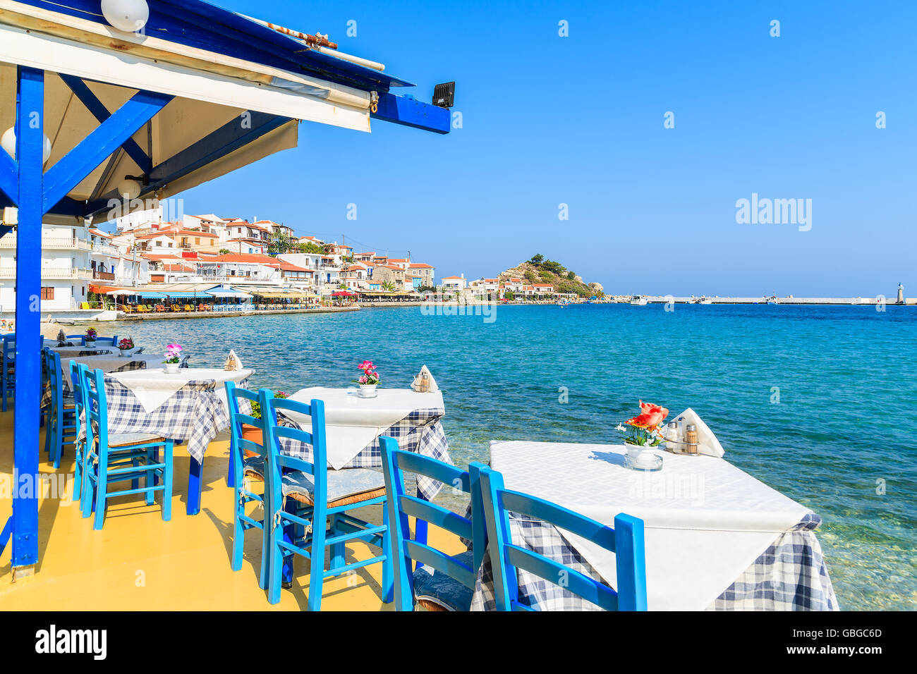 Tables with chairs in traditional Greek tavern in Kokkari town on coast of Samos island, Greece Stock Photo