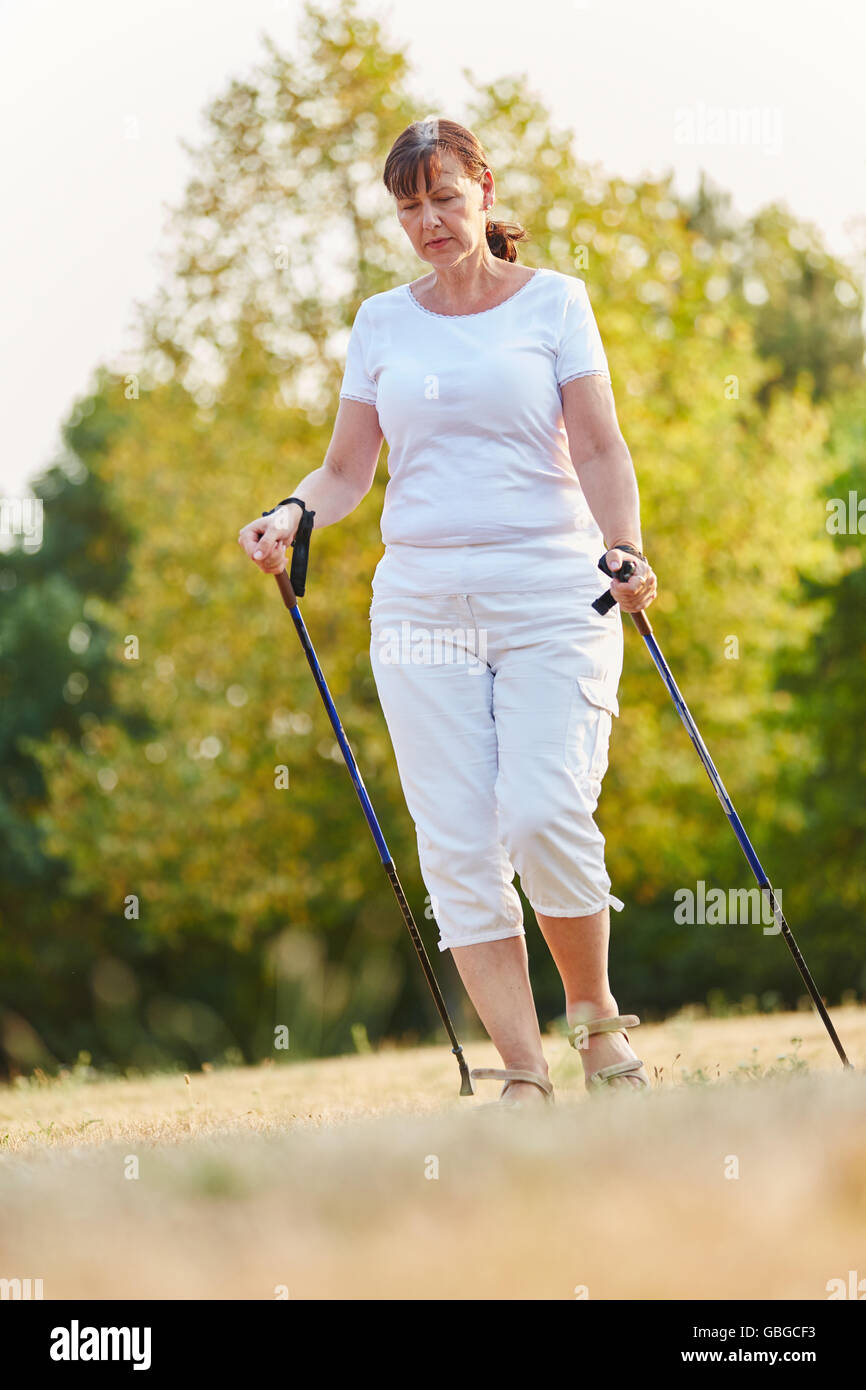 Senior woman during nordic walk with walking sticks in the nature Stock