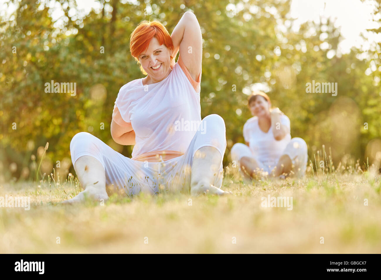 Senior citizens making pilates exercises in the park and stretching Stock Photo