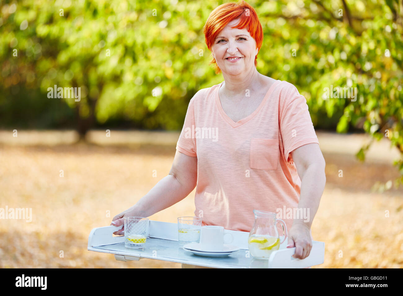Woman holding refreshment drinks on a tablet during her summer vacations Stock Photo
