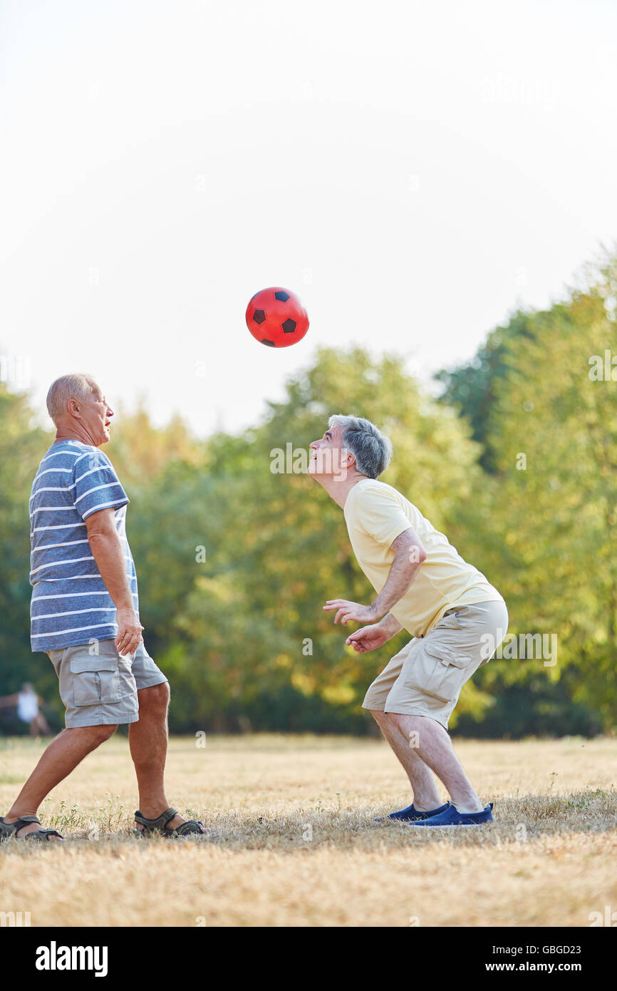 Two active senior friends playing soccer with ther head Stock Photo