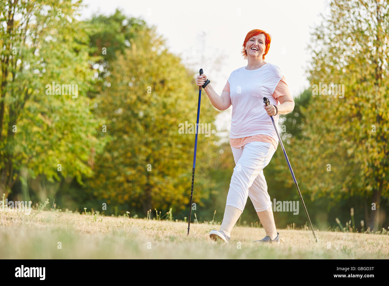 Happy senior woman hiking with hiking sticks in the nature Stock Photo