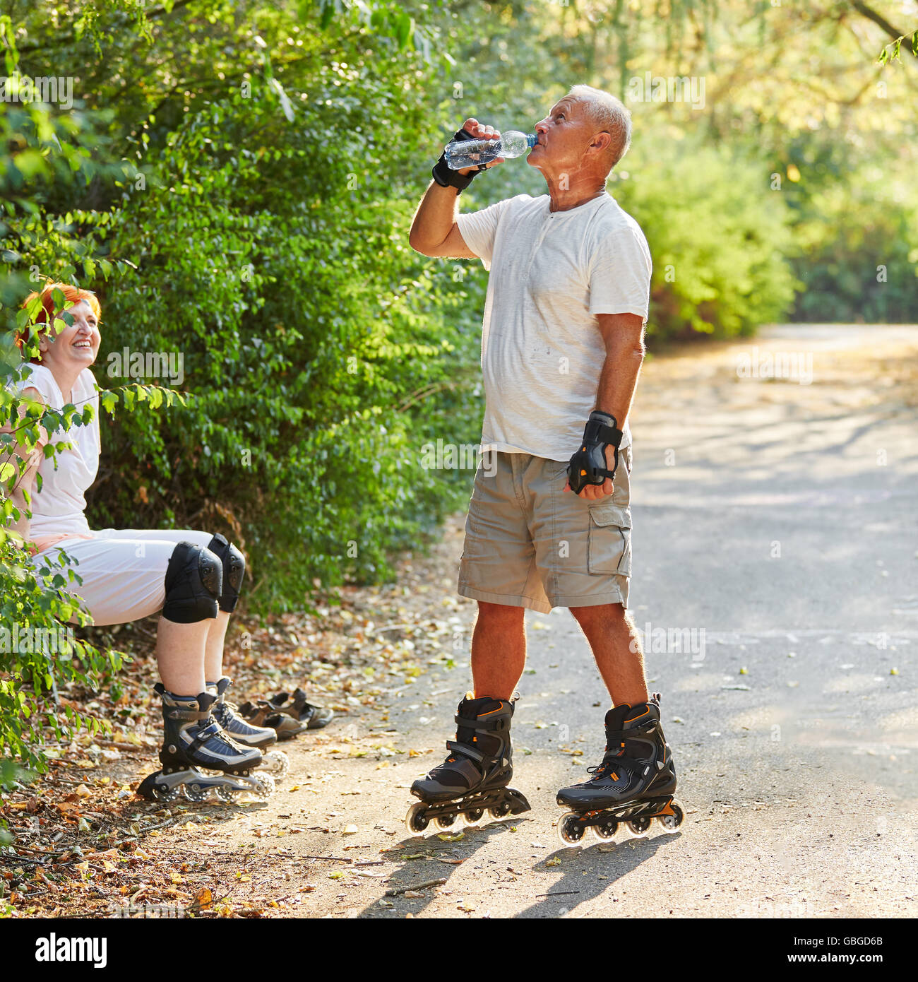Active seniors drinking water after inline skating at the park Stock