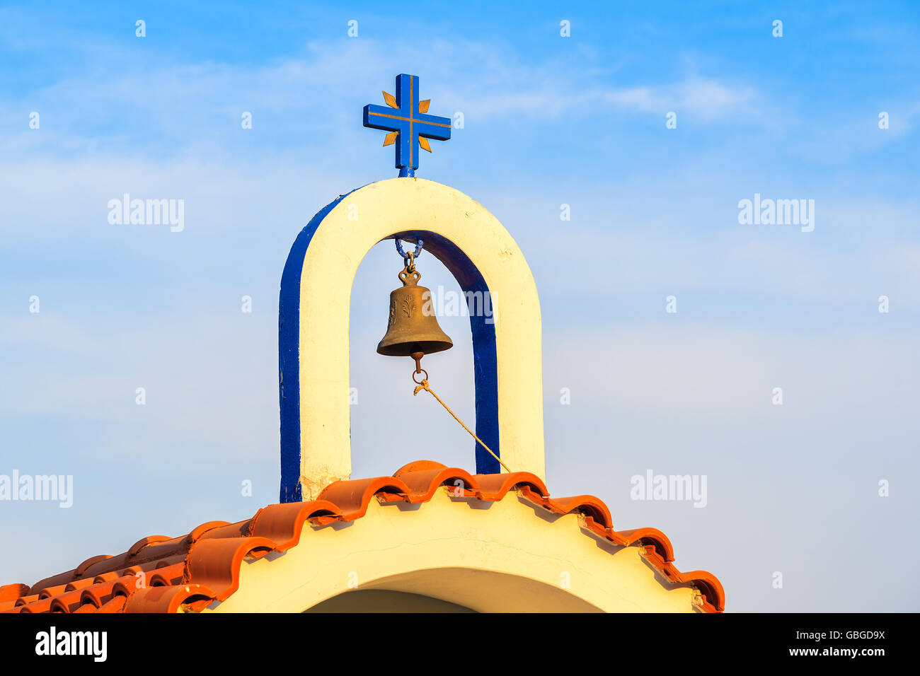 Bell tower of small Greek chapel on coast of Samos island in warm sunset light, Greece Stock Photo